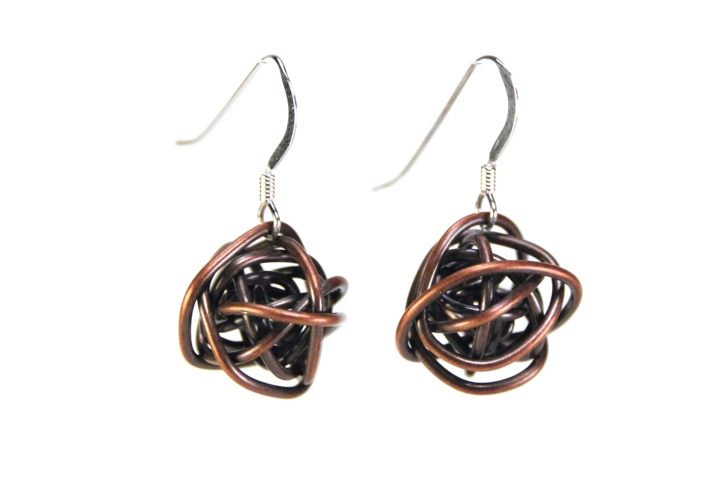 Earrings are antiqued copper wire wrapped loosely into a ball. The copper is darkened to brownish-black, with the outer surfaces sanded to reveal highlights of the orange-brown color of copper.