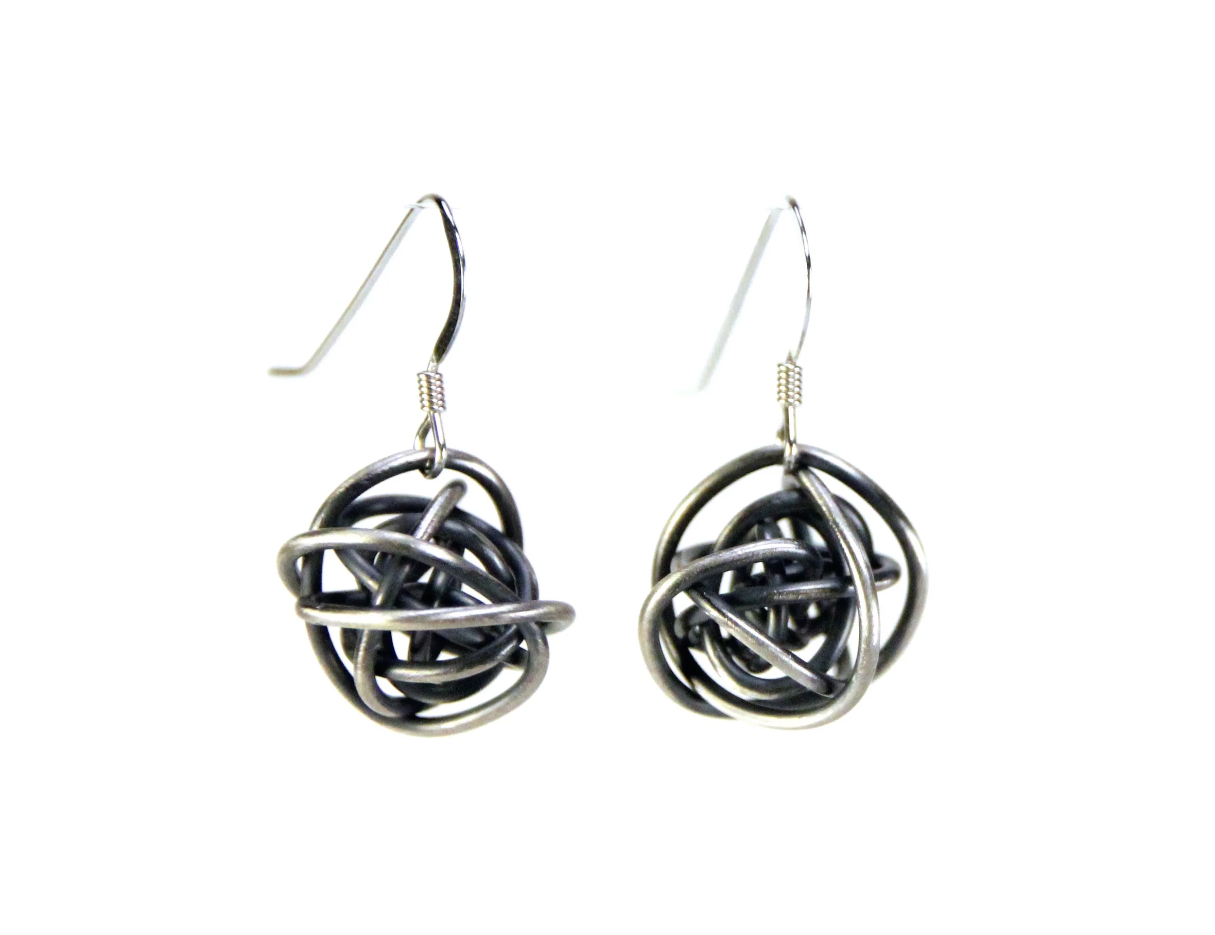 Earrings are sterling silver wire wrapped loosely into a ball. The silver is darkened to grayish-black, with the outer surfaces sanded to reveal highlights of the bright silver color.