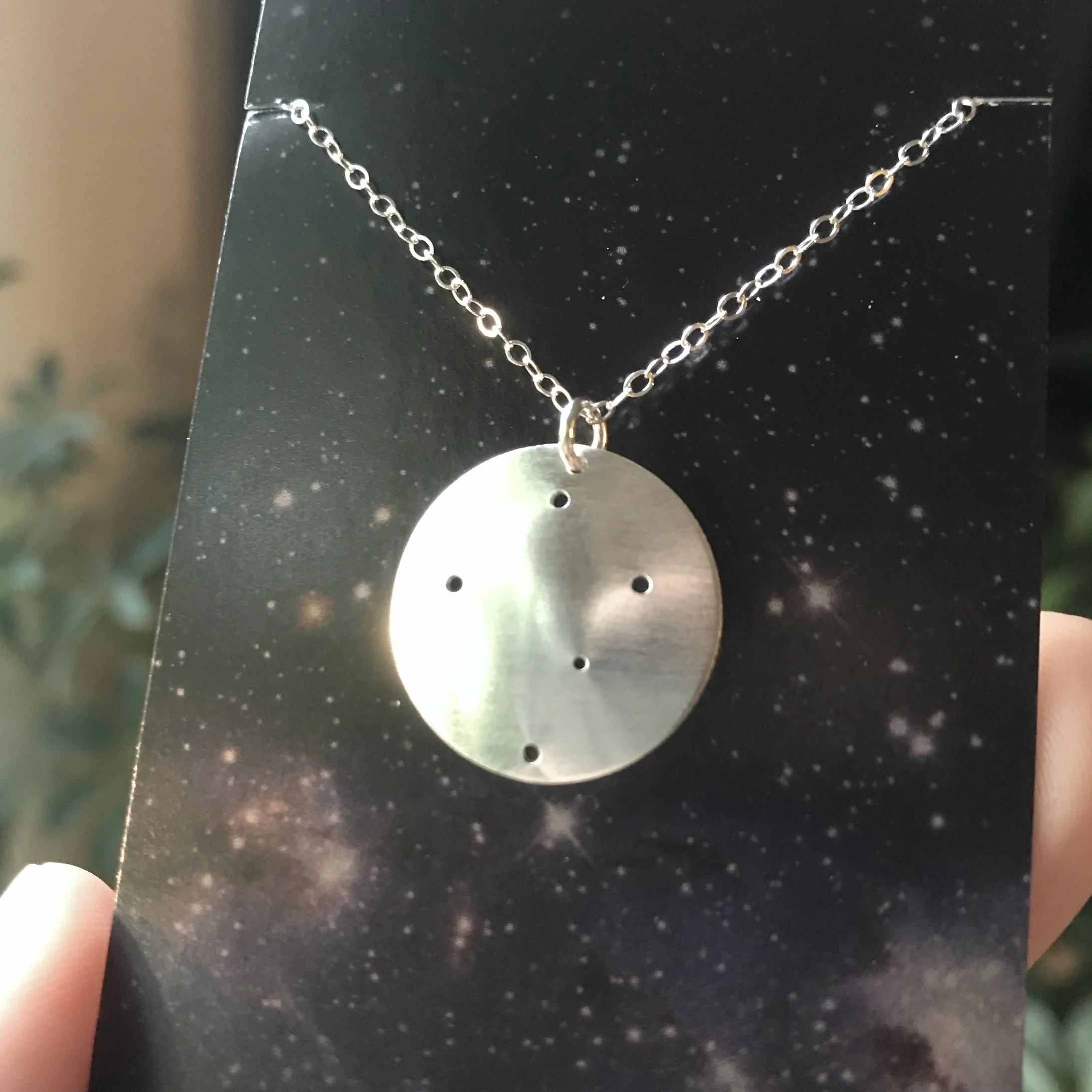 Round brushed silver pendant has 5 small holes drilled to match the Crux constellation. Pendant is slightly domed and attached to an open-link silver chain with a silver jump ring.