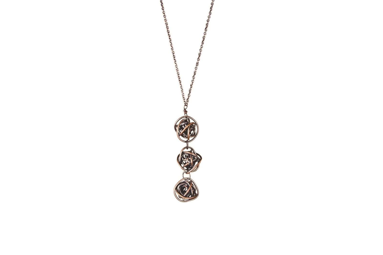 Necklace has 3 loosely wrapped copper wire balls hanging vertically from a narrow antiqued copper chain. The copper wire is darkened, with the outsides sanded to show highlights of raw copper.