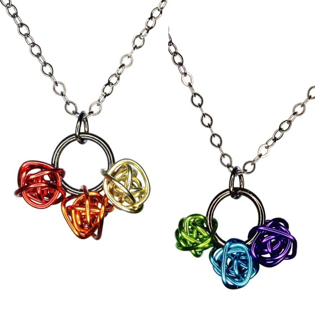 Each pendant has 3 loosely wrapped small colorful shiny wire balls. The balls are strung on the bottom of a shiny black metal ring. Image shows two color options – cool and warm.