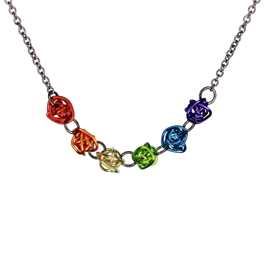 Necklace has 6 colorful loosely wrapped wire balls attached horizontally by jump rings in order of the rainbow - red, orange, yellow, green, blue, and purple. The wire is shiny and smooth.