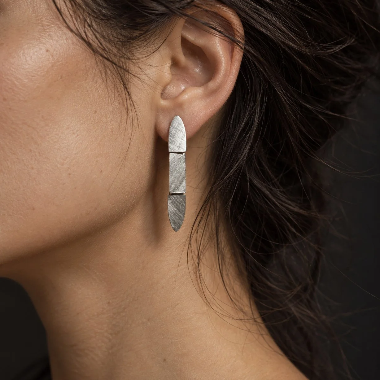 Contemporary Florentine-finish silver drop earrings worn on the ear, featuring delicate articulated sections, subtle texture and graceful movement.
