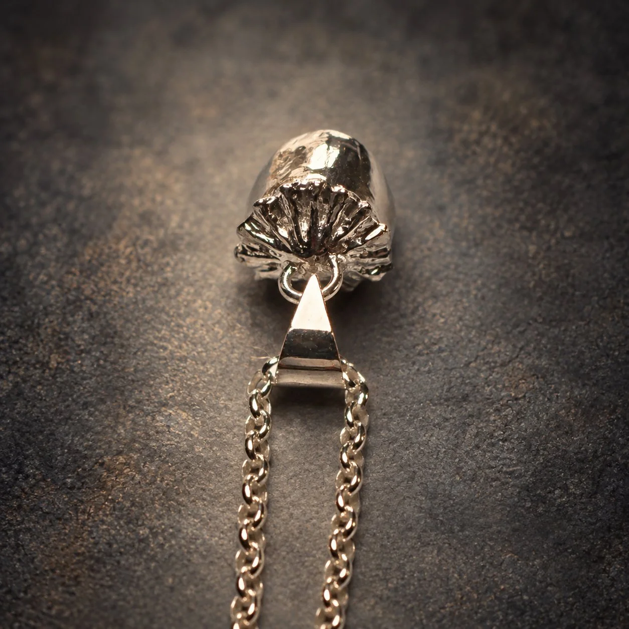 Detail of handmade sterling silver poppy pod pendant showing the textured seed capsule crown