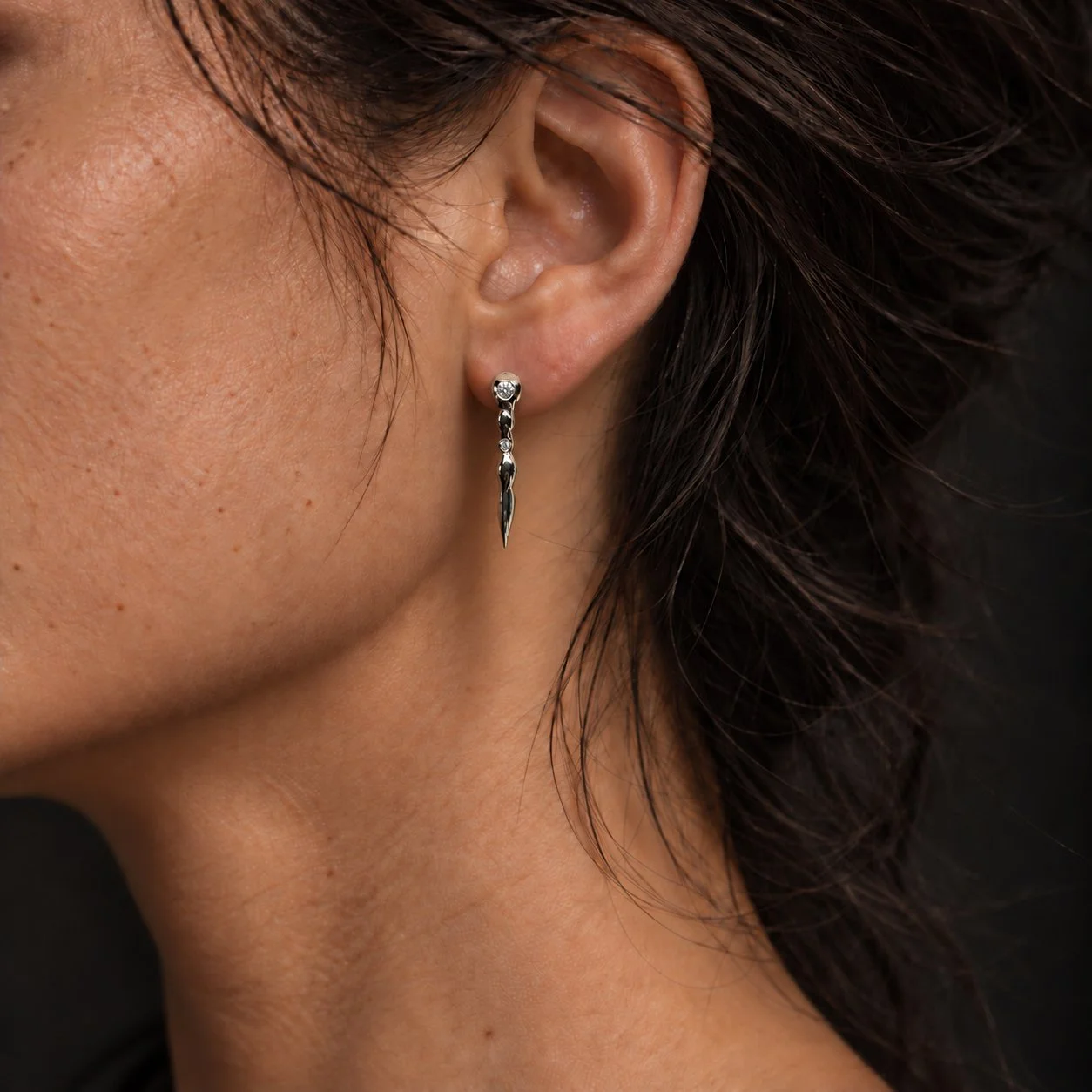 woman wearing Cascata hand-carved sterling silver drop earrings with two flush-set diamonds in each earring