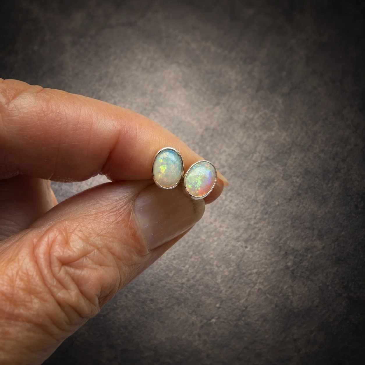 natural opal silver stud earrings, in fingers to show size