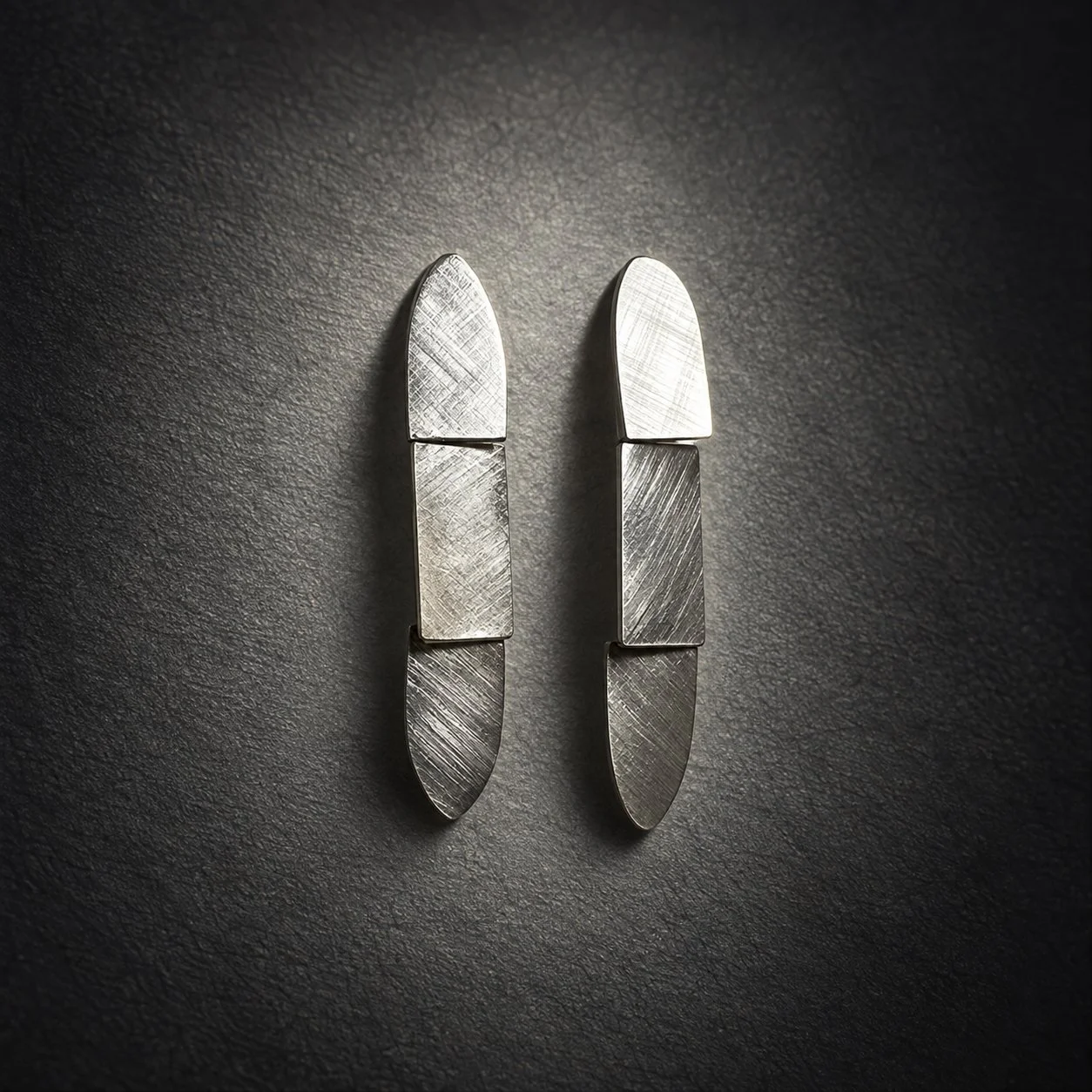 Handcrafted sterling silver drop earrings with a textured Florentine finish, articulated geometric sections and an elegant sculptural design.
