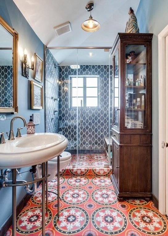 a-maximalist-bathroom-with-blue-walls-and-blue-tiles-a-red-mosaic-tile-floor-a-stained-storage-cabinet-and-a-smal-gallery-wall.jpg