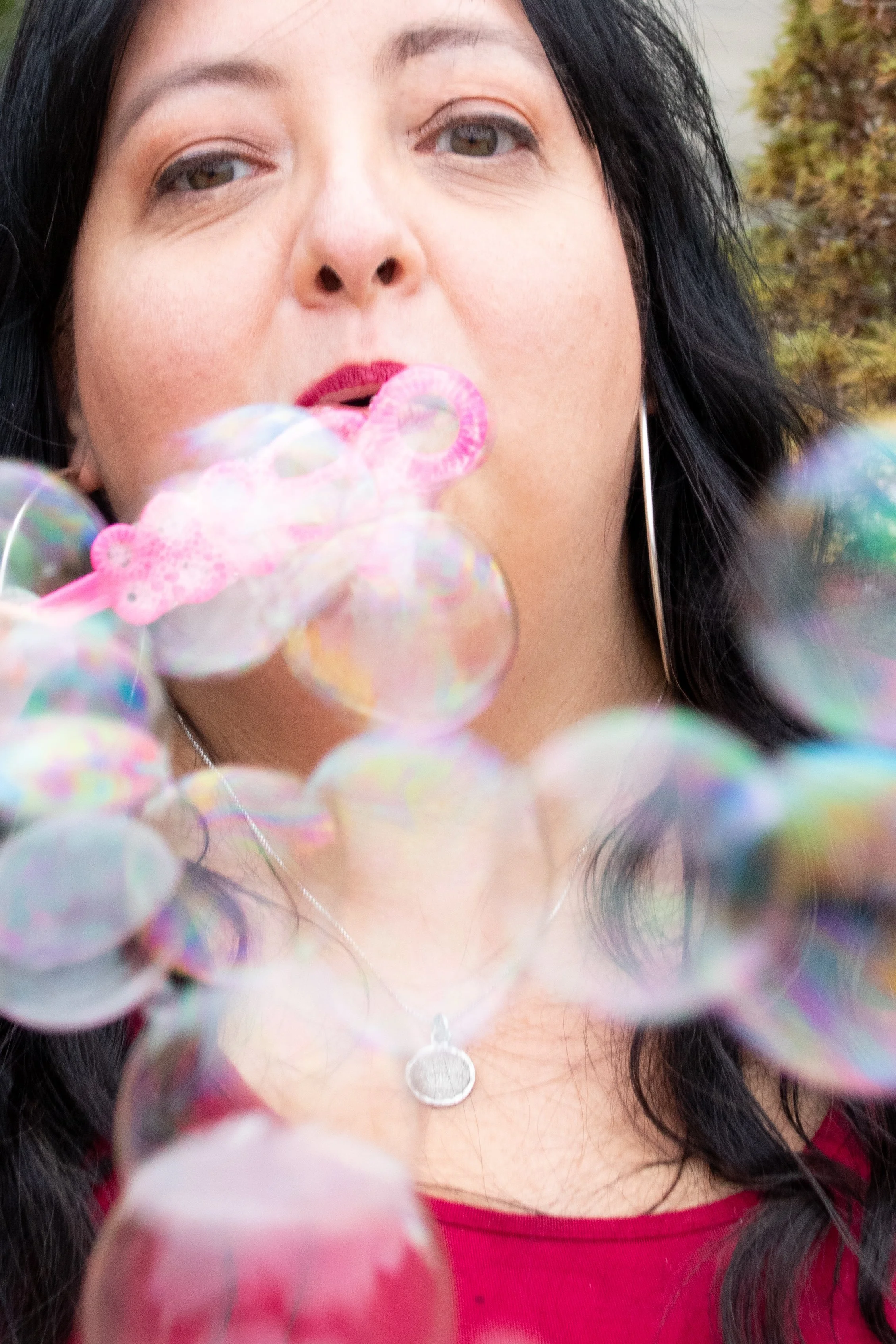 woman in red dress blows bubbles