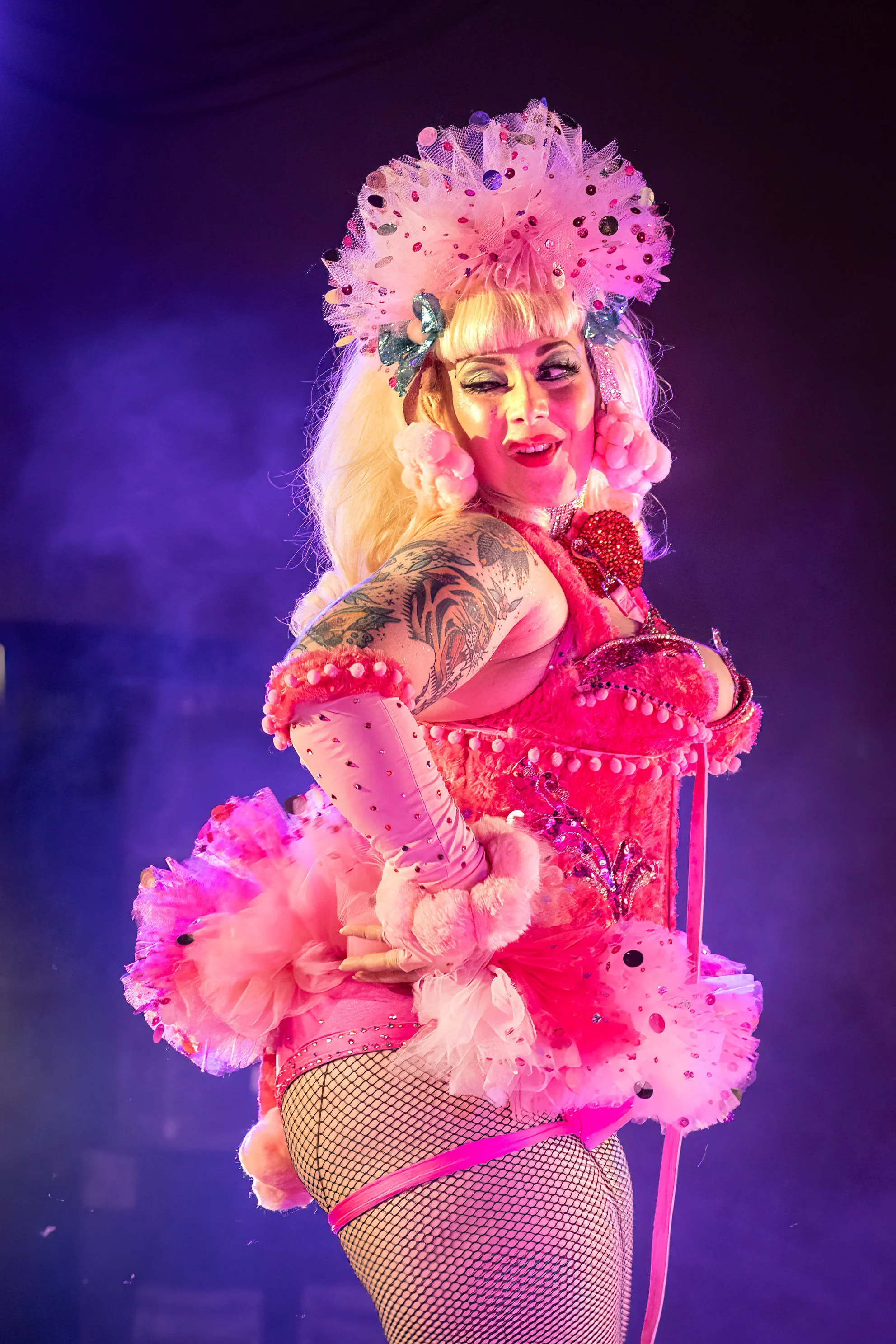burlesque performer in fun pink outfit winking at audience