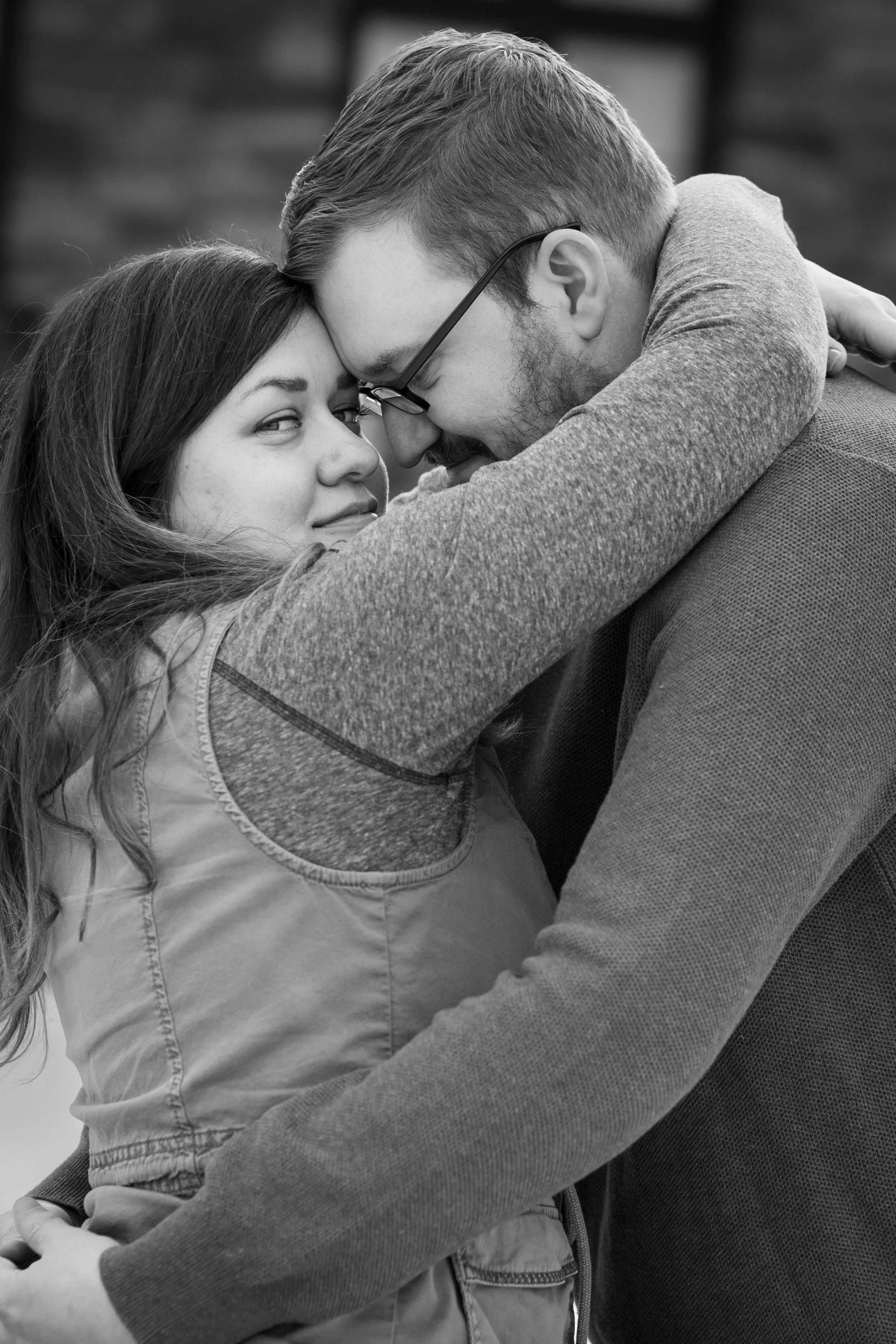 couple hugs while woman looks slyly at camera