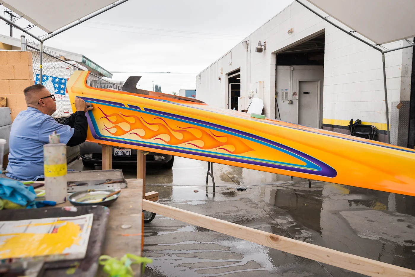 Galvez paints a youth dragster under a tent in the rain. He says this is the most fun he's had on a project in a long time. As he was striping, it was cold enough that Galvez couldn't feel his fingers.