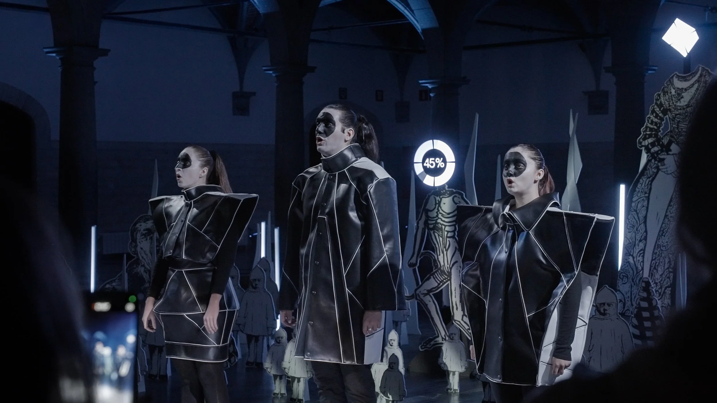 Close-up of singers in contemporary costumes performing within Mécaniques Discursives installation