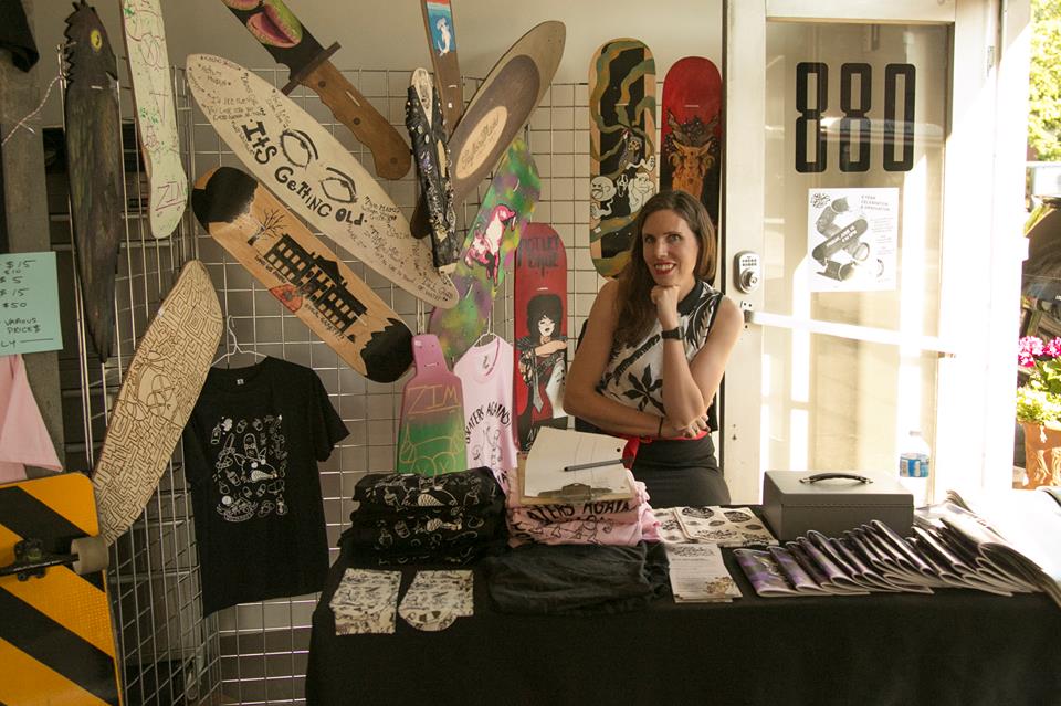 Oasis teacher Lauren holding down the merchandise table with tons of student-made boards, clothing and zines that support the ongoing program. 