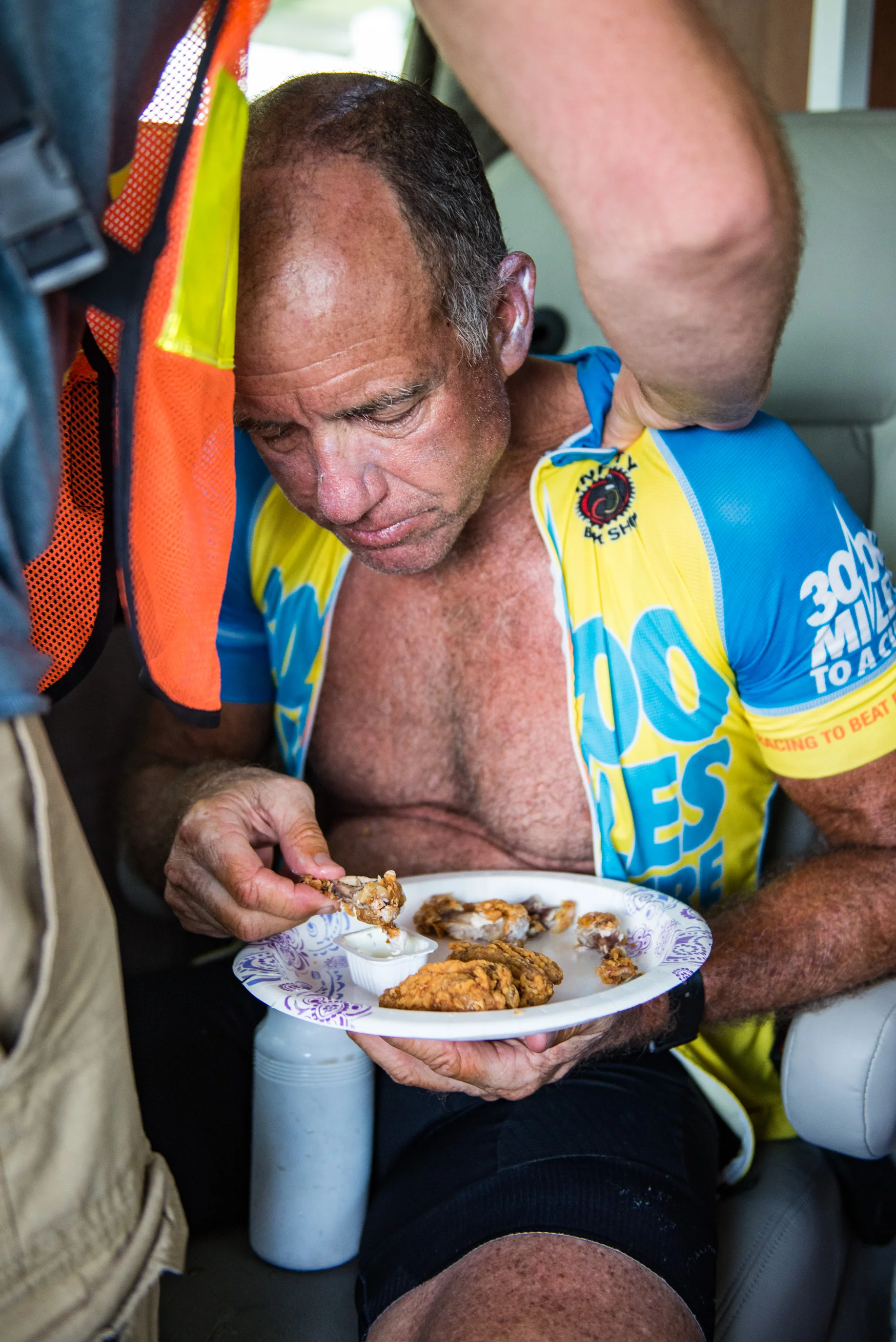 Marshall eats KFC wings that his crew had bought for him as crew member Jacob Bouchard massages his back. Marshall was exhausted but had 3 days of 20 hour rides ahead of him before the finish. Photo taken on June 23rd, 2016.