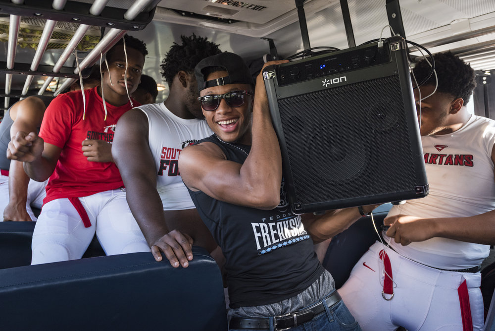 Southern Durham junior wide receiver Devin Smith carries the team speaker inside of the bus. Smith, one of the team's best players, was not playing due to injury but that did not stop him from starting the party before the game. 
