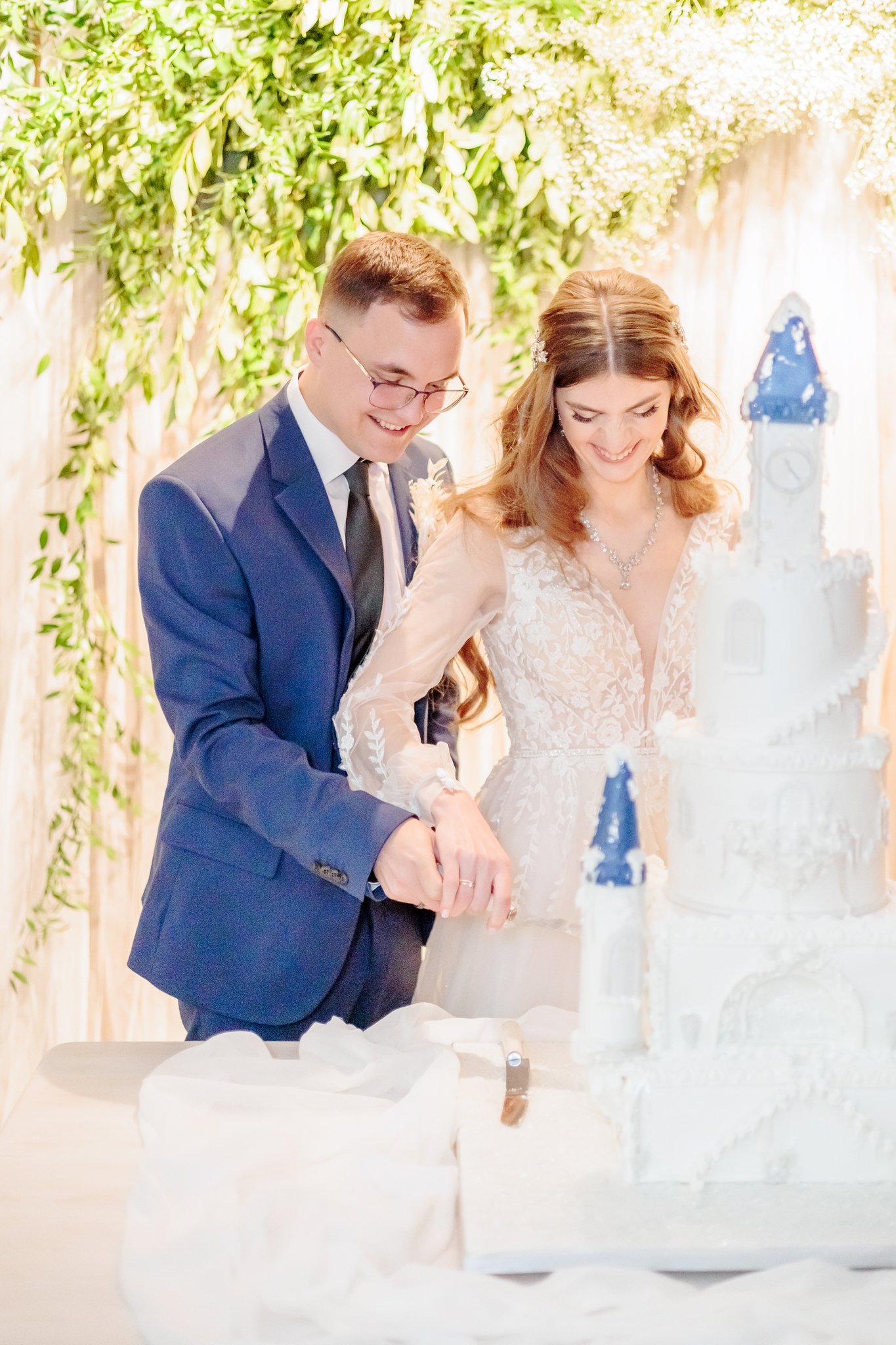 young Ukrainian couple cutting their winter castle themed wedding cake Savvy Leigh Photography