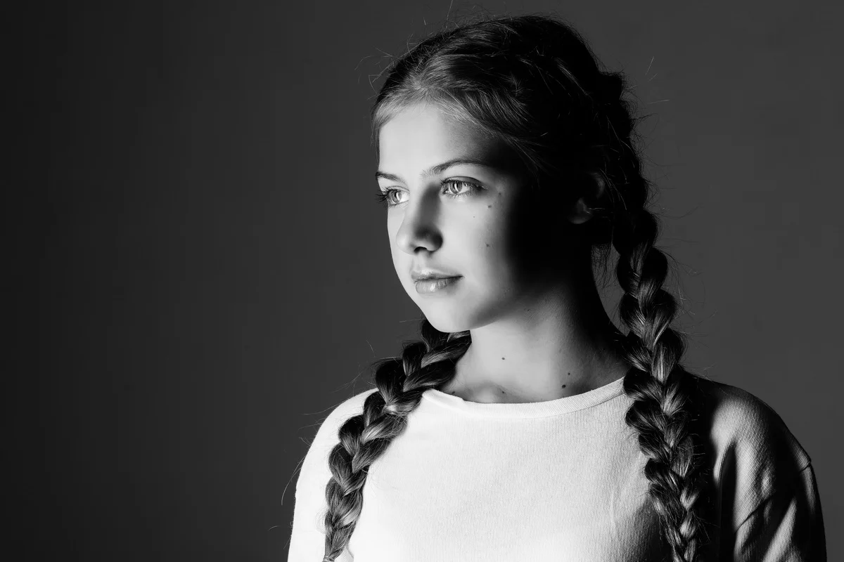 Black and white portrait of a young woman with braided hair, looking to the side with a calm expression.