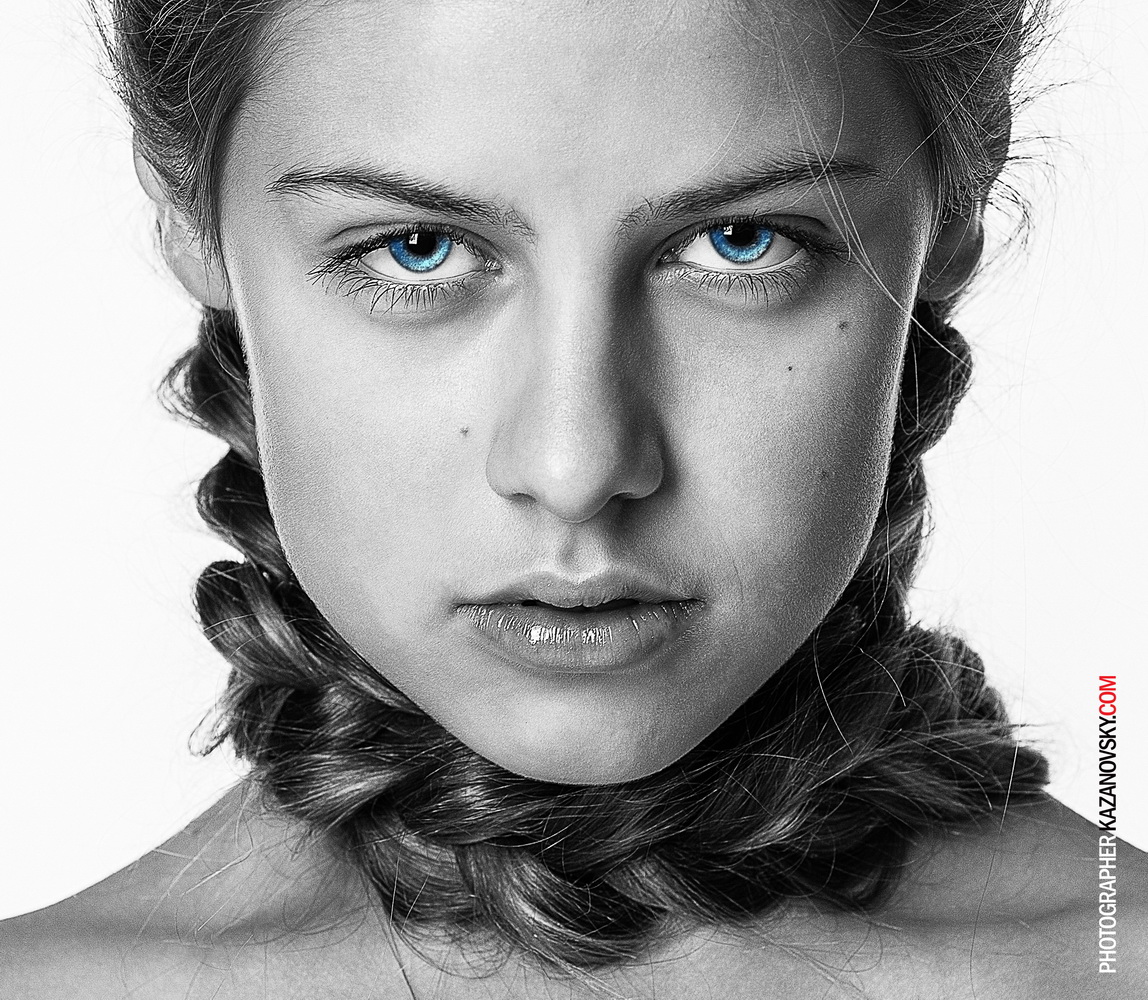 Close-up black and white portrait of a young woman with striking blue eyes and curly hair.