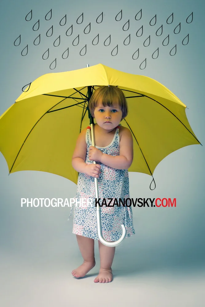 A young girl holding a yellow umbrella, standing barefoot on a plain background. The girl has a serious expression and is wearing a sleeveless dress. There are black teardrop shapes drawn on the wall behind her.