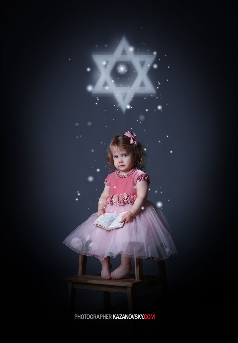 A young girl in a pink dress and floral belt sitting on a wooden chair, holding an open book, with glowing white star and hexagram symbols above her and floating particles around her in a dark background.