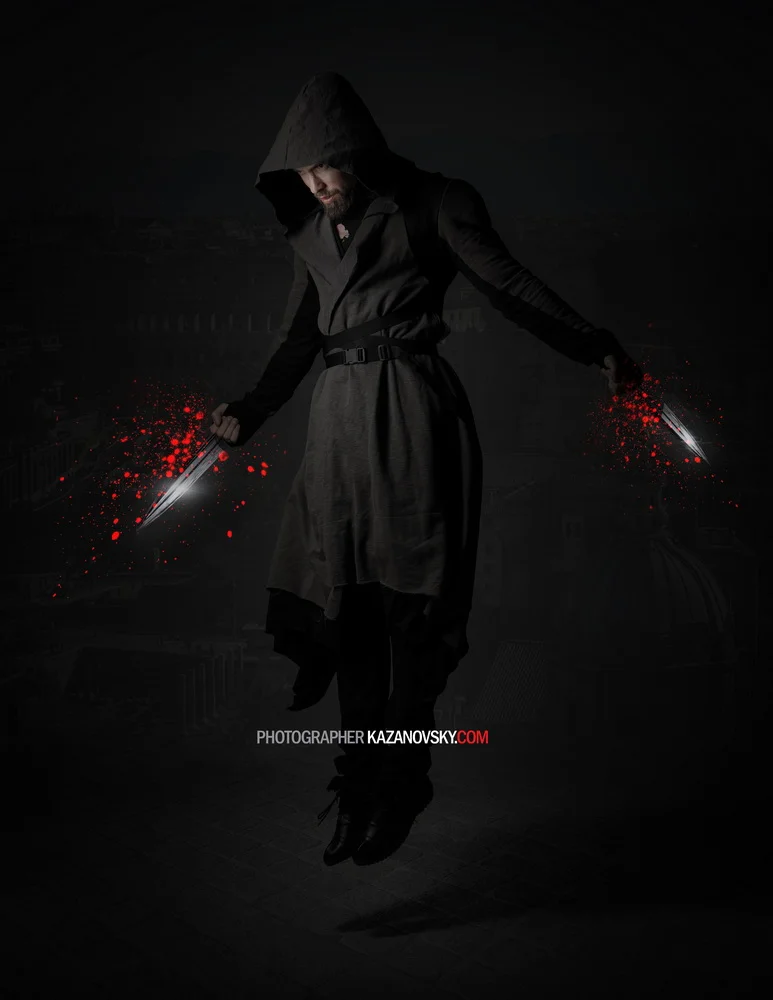 A man in a dark hooded coat with a hood covering his head, floating in mid-air against a dark background. He is holding two glowing knives, one in each hand, with red sparks or splatters around them.