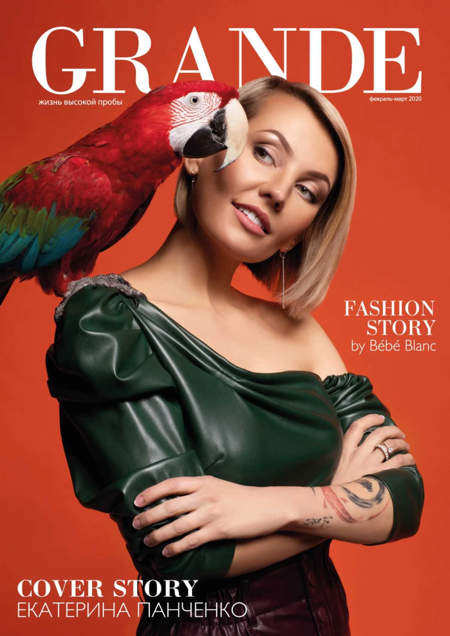Magazine cover featuring a woman with short blonde hair and a green leather top, with a colorful parrot perched on her shoulder. The background is orange, and the text includes the magazine title 'GRANDE', the date 'February-March 2020', and headline
