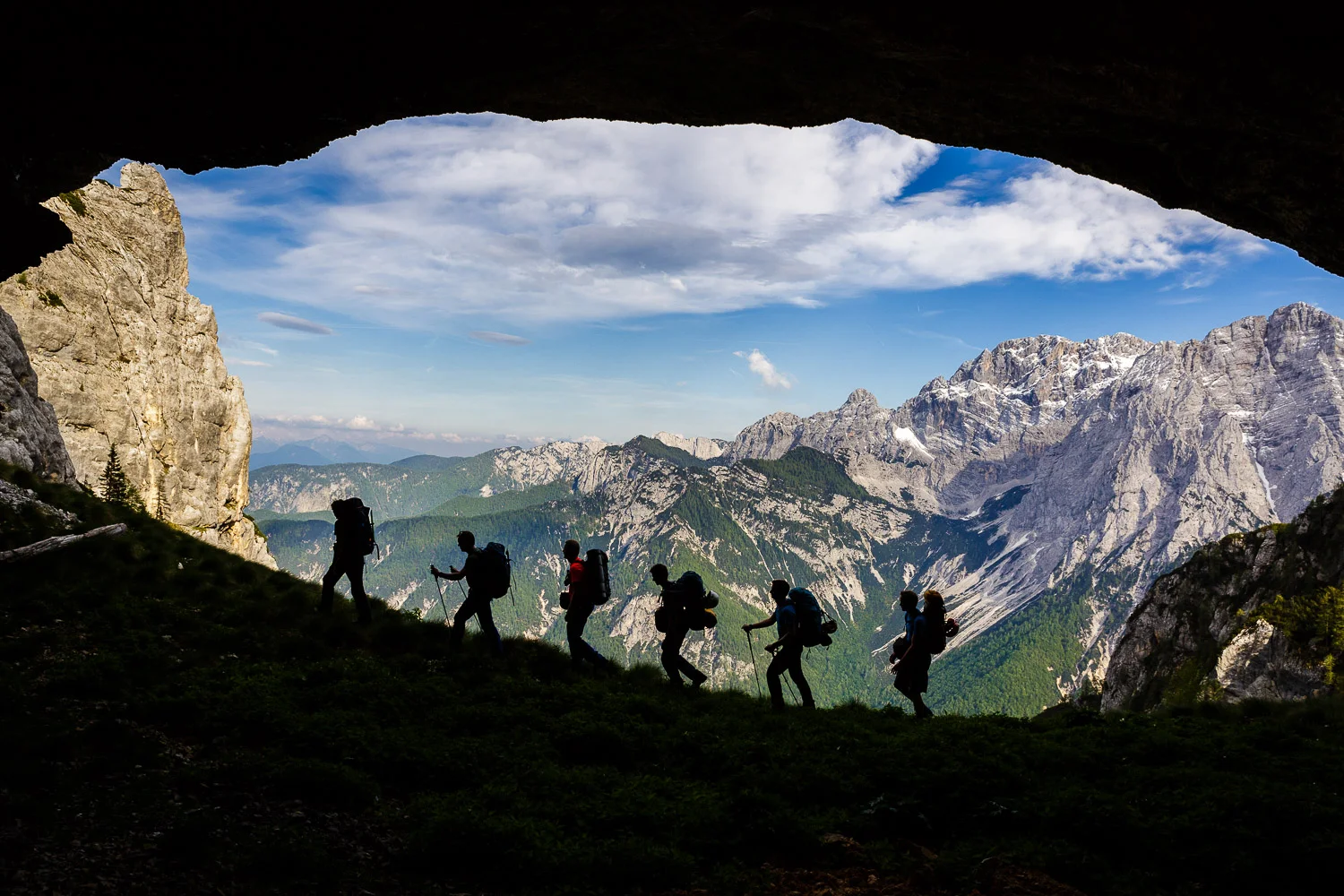Hikers passing by a hole in the wall, Julian Alps, Slovenia