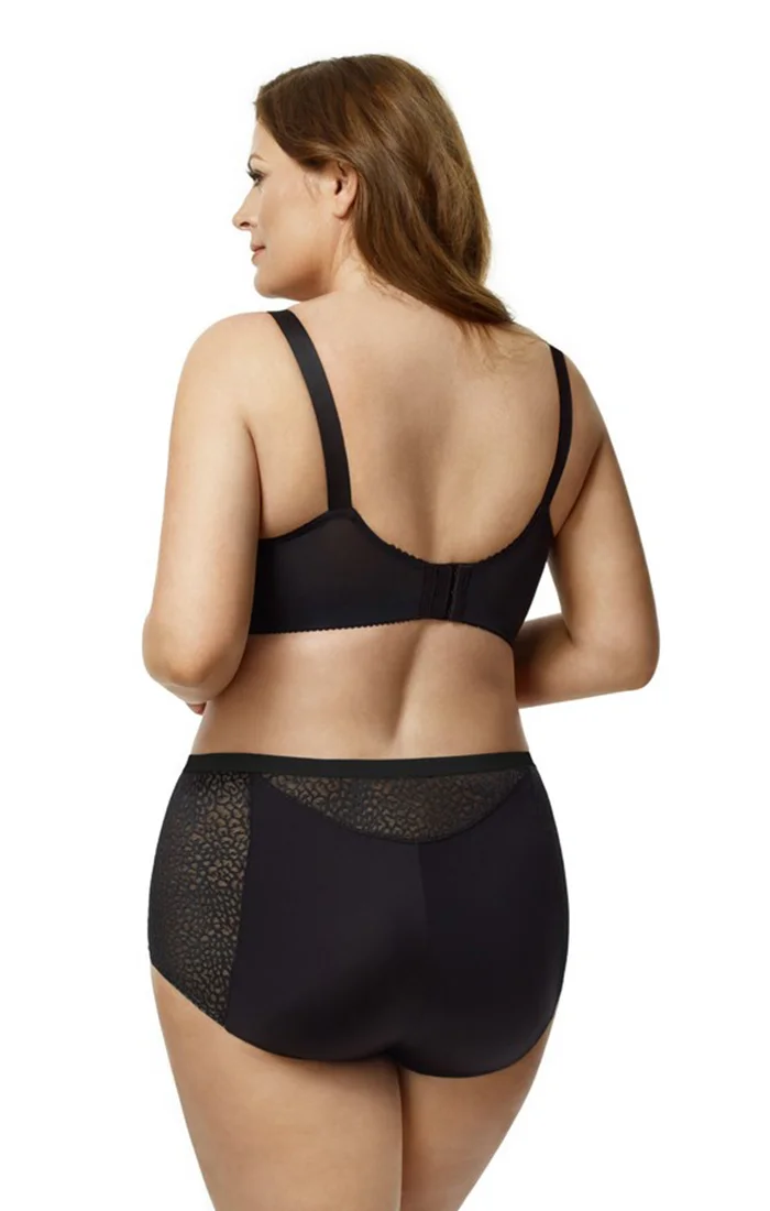 A woman with reddish-brown hair wearing black lingerie, including a bra and high-waisted panties, standing with her back facing the camera against a plain white background.