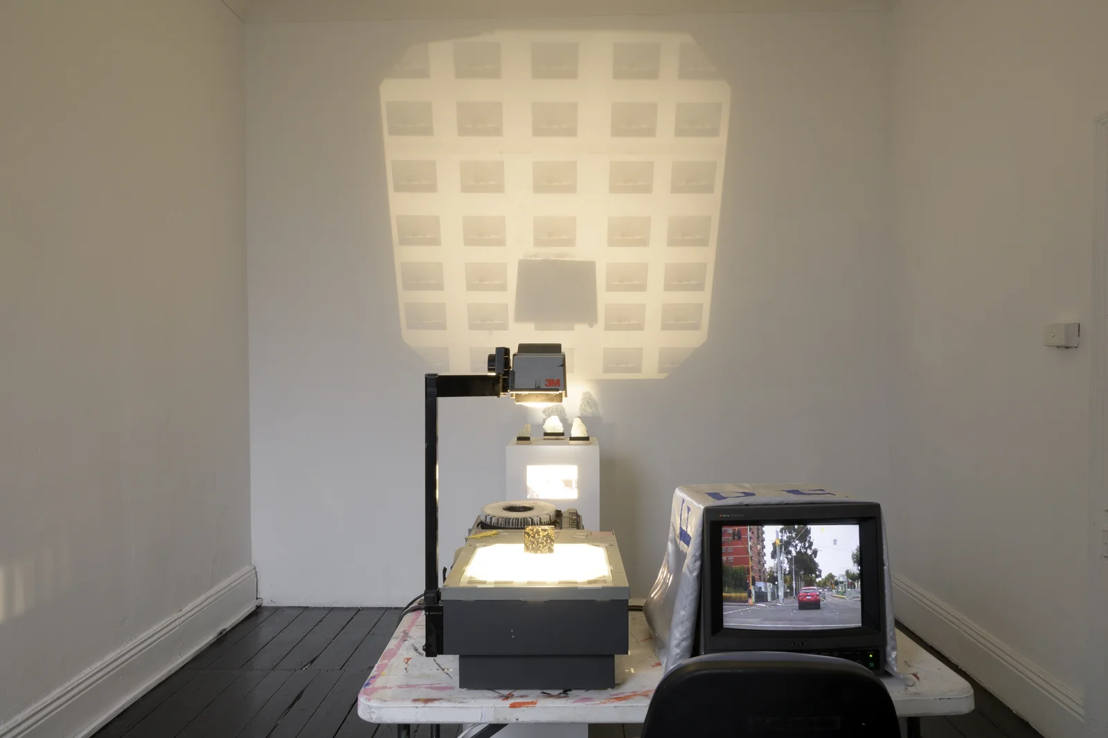 Peter Narzisi, DashCAM (redundant act(s)) // Arnie’s Back // Bus Shelter Kintsugi // Assessment Install . Silk, glass, gold enamel, 3 plinths, overhead projector, hacked Kodak ektapro 3000, TV. 2019.