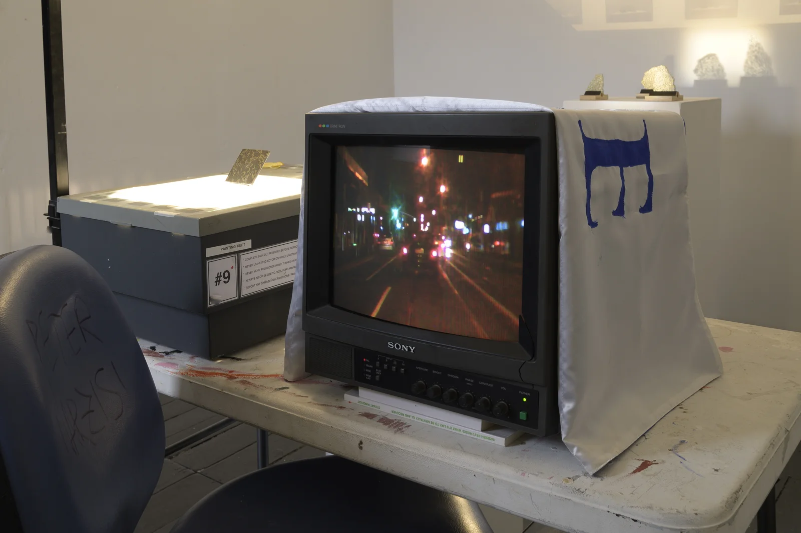 Peter Narzisi, DashCAM (redundant act(s)) // Arnie’s Back // Bus Shelter Kintsugi // Assessment Install . Silk, glass, gold enamel, 3 plinths, overhead projector, hacked Kodak ektapro 3000, TV. 2019.