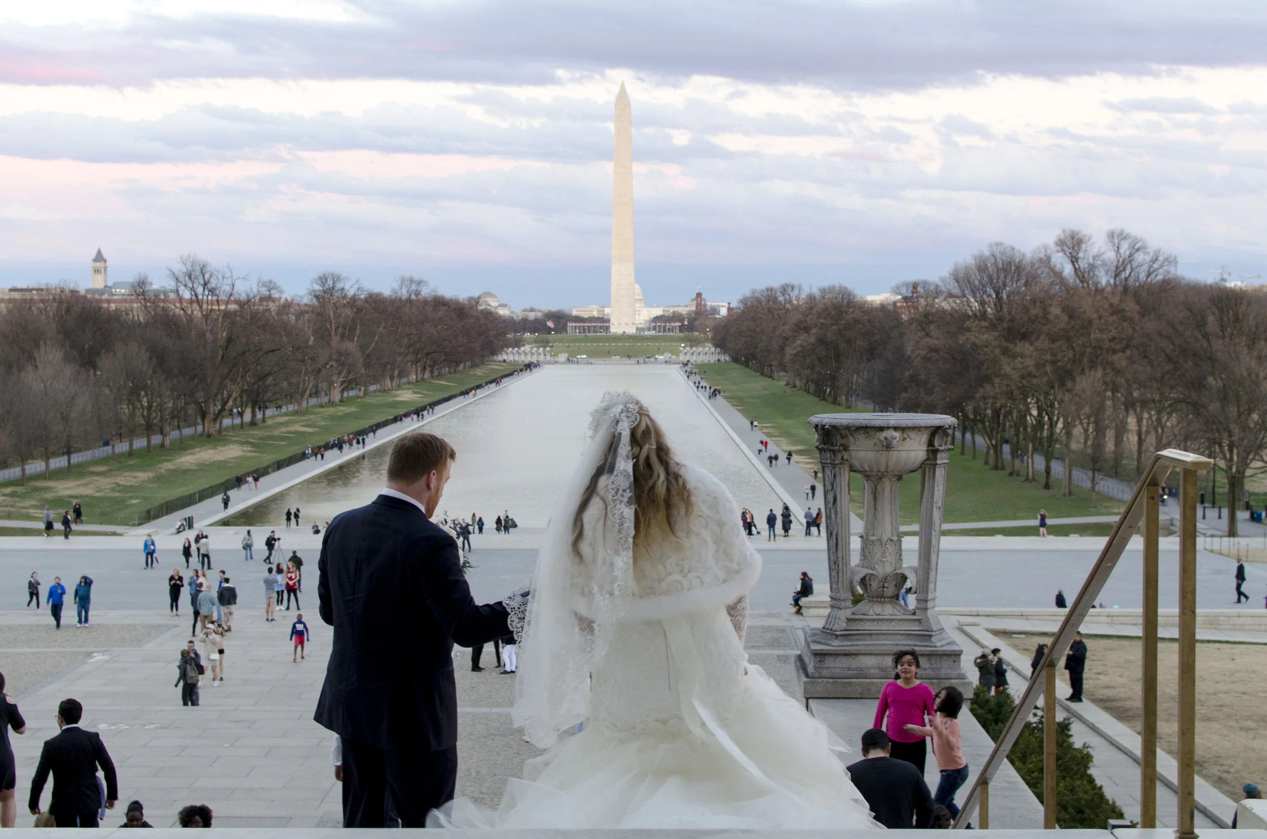  A bride and groom walk down the steps in front of the Lincoln Memorial. 