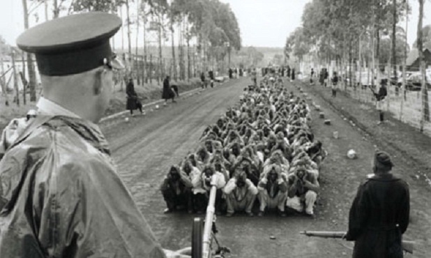 Captured participants in the Mau Mau rebellion watched over by British colonials in Kenya