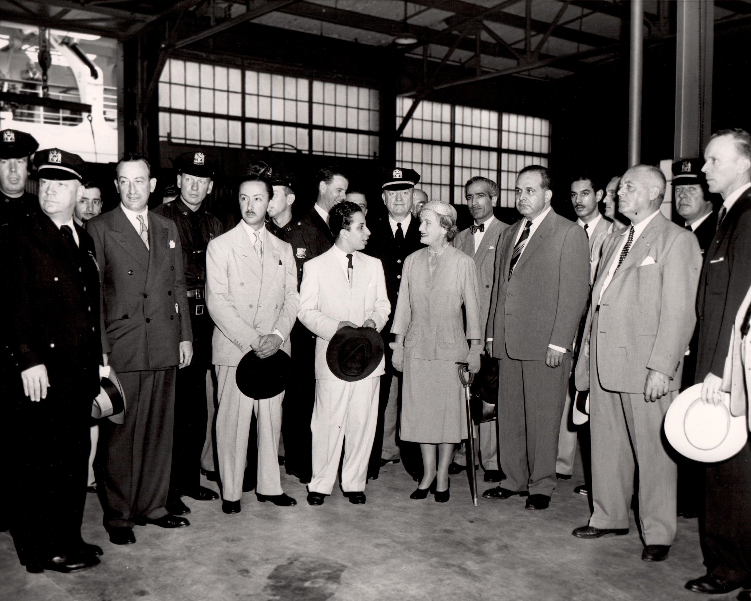 Disembarkation at Pier 90 King Faisal II (center) flanked by escorts; standing in front, second from the left is John Coleman, Vice Chairman of the Mayor’s Reception Committee, with Prince-Regent Abdul Ilah between Coleman and Faisal