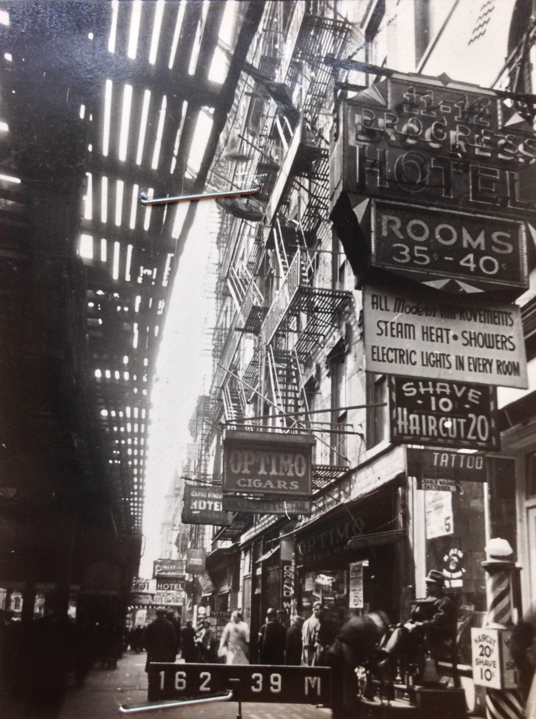 7 Chatham Square, Manhattan, circa 1940. The elevated train tracks, once part of the IRT Third Avenue Line, have been demolished. Prices on signs include 35 cents for a hotel rooms and a 10 cent barber shop shave. Department of Finance Collection, NYC Municipal Archives.