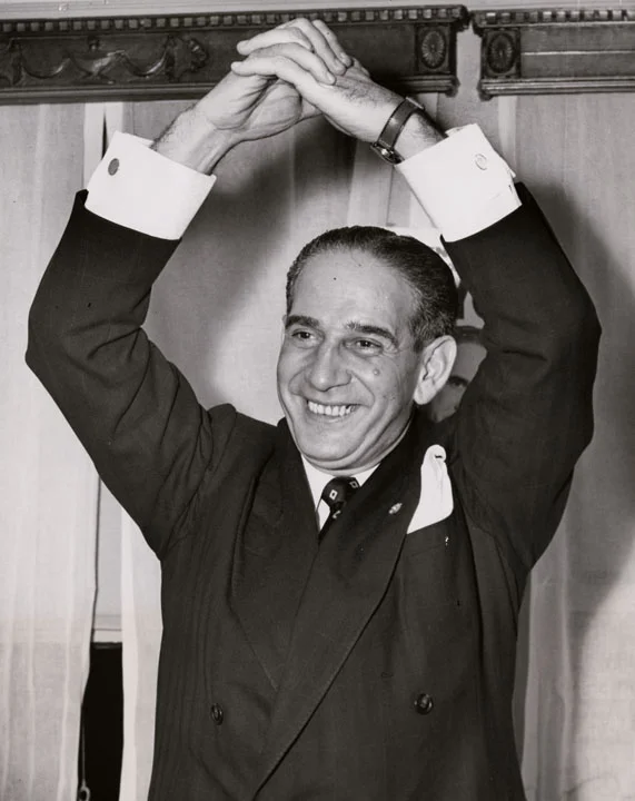 Newly elected Mayor Vincent R. Impellitteri gives a Victory Handshake at his headquarters in the Hotel Abbey on November 7, 1950. Impellitteri became Acting Mayor on September 2, 1950, upon the resignation of Mayor William O’Dwyer and won a full four-year term in a special election on November 7, 1950. ACME News Photos, Mayor Wagner Papers, NYC Municipal Archives.