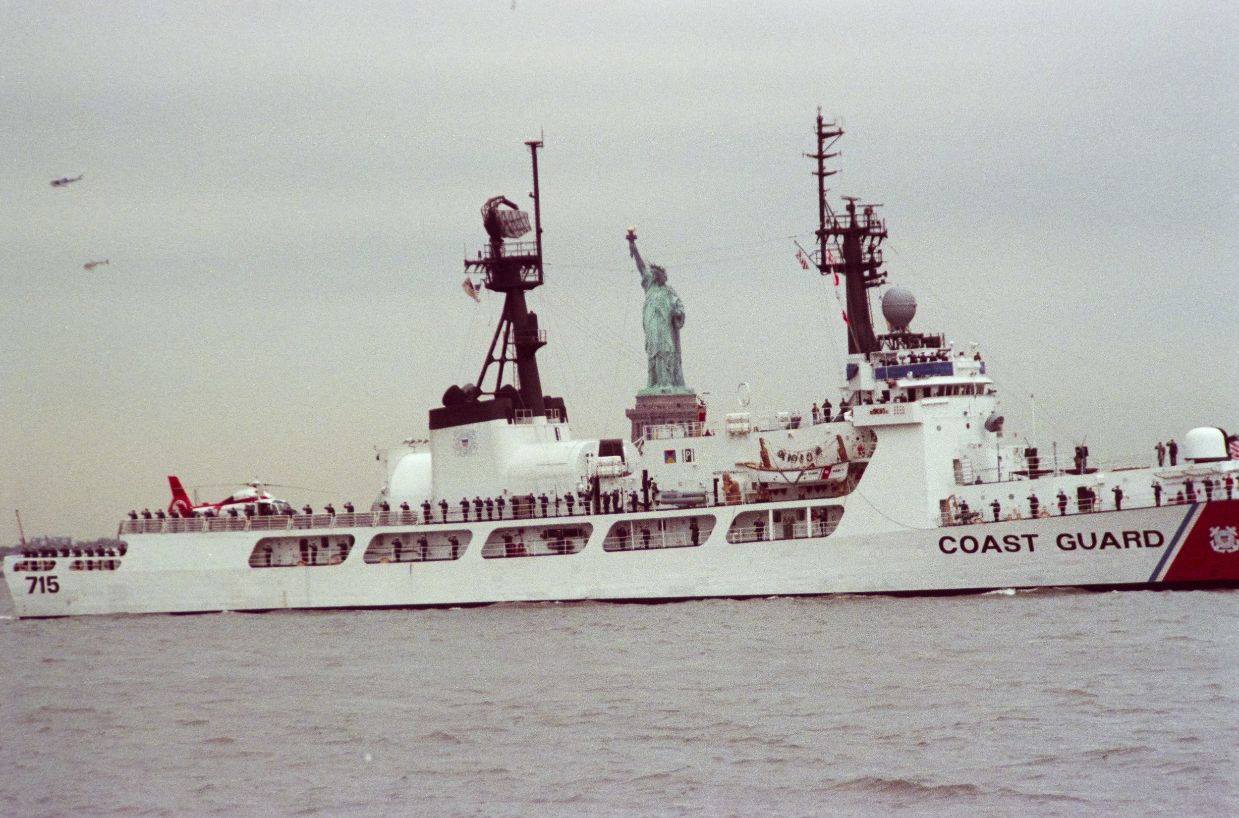 Coast Guard ship passing in front of the Statue of Liberty during the parade of ships, April 29, 1989, photographer Joan Vitale Strong. Mayor Edward I. Koch Collection, NYC Municipal Archives.