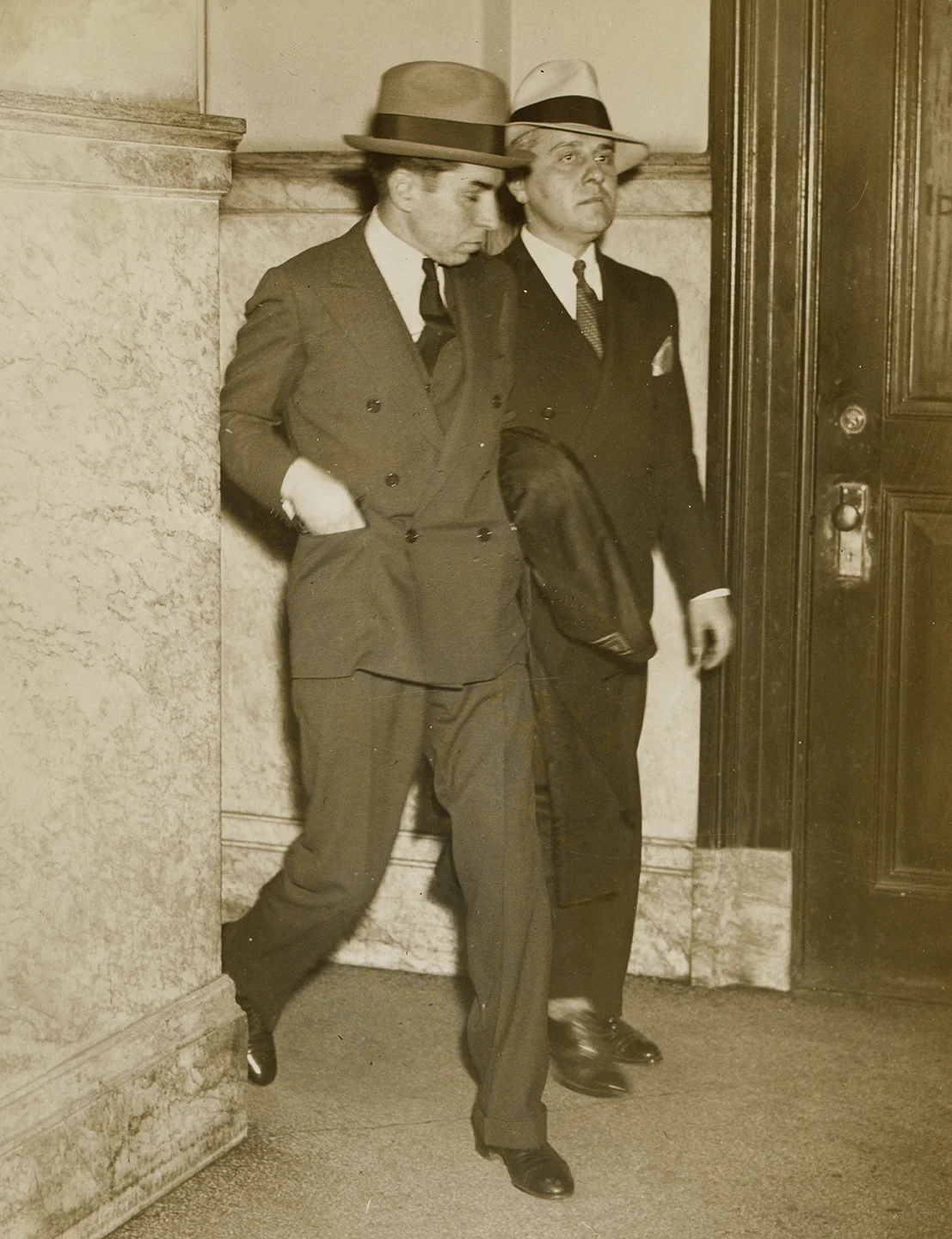 Lucky Luciano (left) enters police headquarters with detective on arrival from Little Rock, April 18, 1936. NYC Municipal Archives Collection.