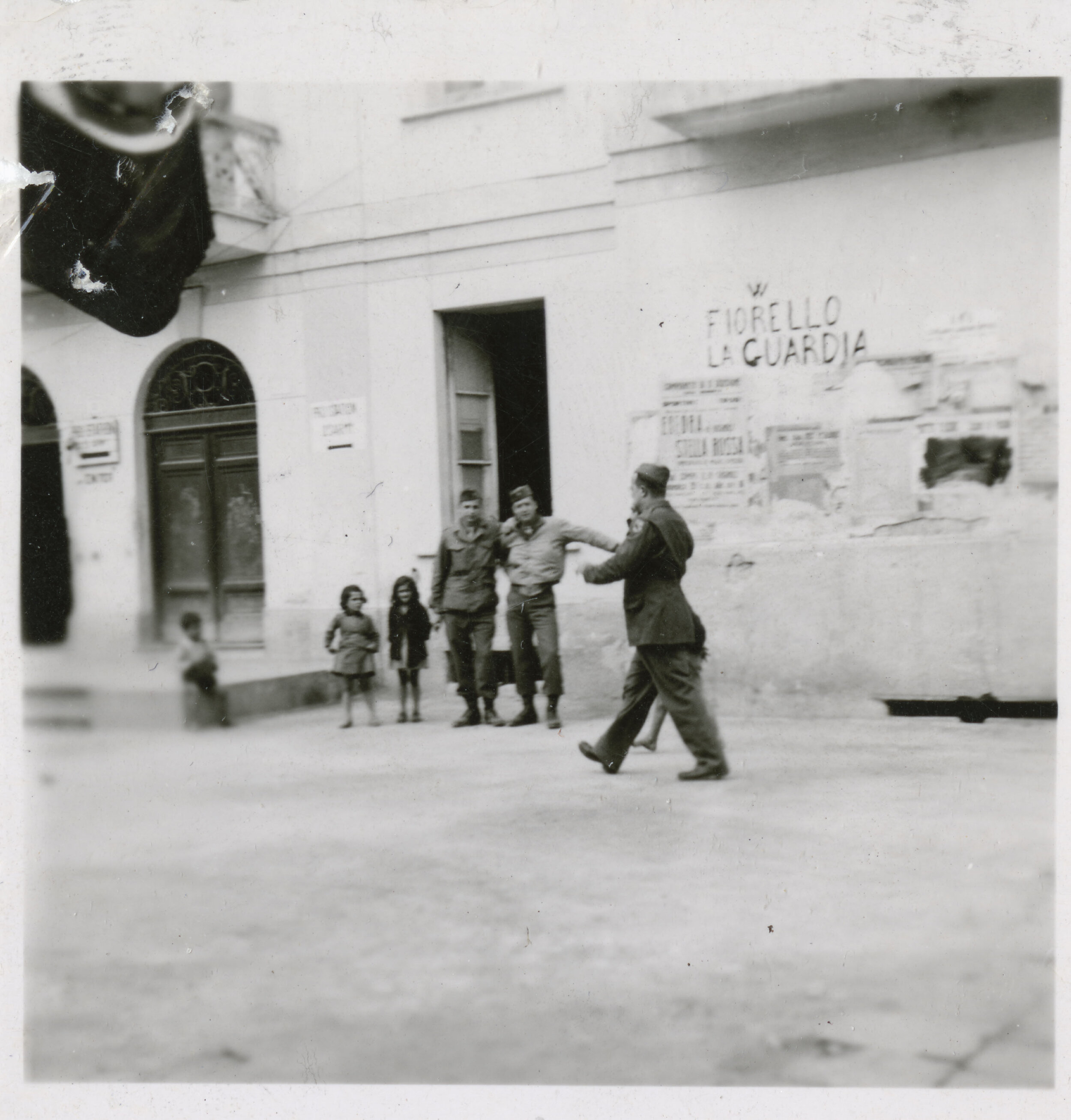 American G.I.s and local children in front of a wall painted with “Fiorello LaGuardia,” and a crown victory symbol, Pozzvoli, Italy, 1945. Mayor LaGuardia Collection, NYC Municipal Archives.