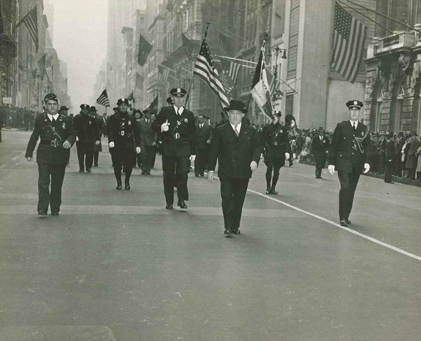 Mayor LaGuardia marching at head of Columbus Day Parade, flanked and followed by policemen, October 12, 1943. Mayor LaGuardia Collection, NYC Municipal Archives.