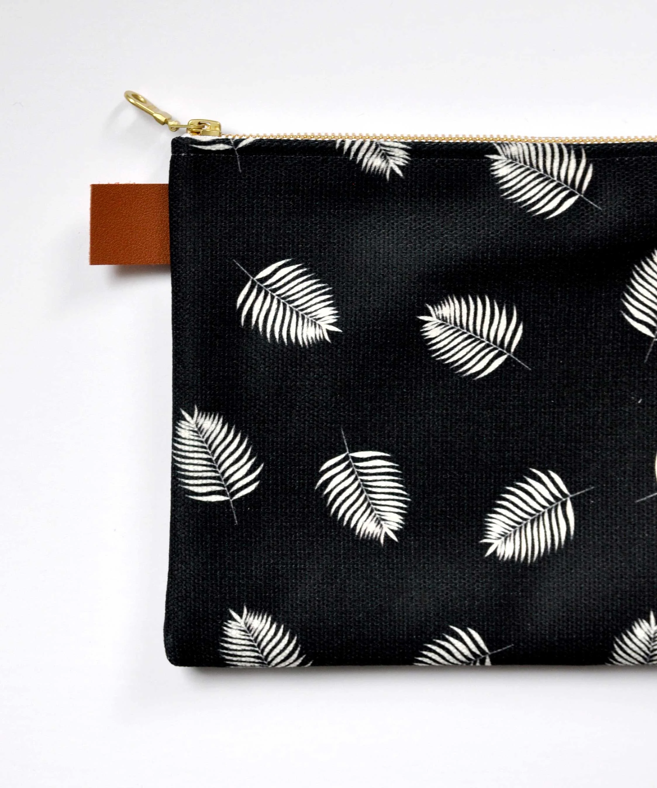 Palm leaf patterned canvas pouch. Designed by Swell Made Co. and made in Canada. Brass zipper and pull with vegan leather tag.