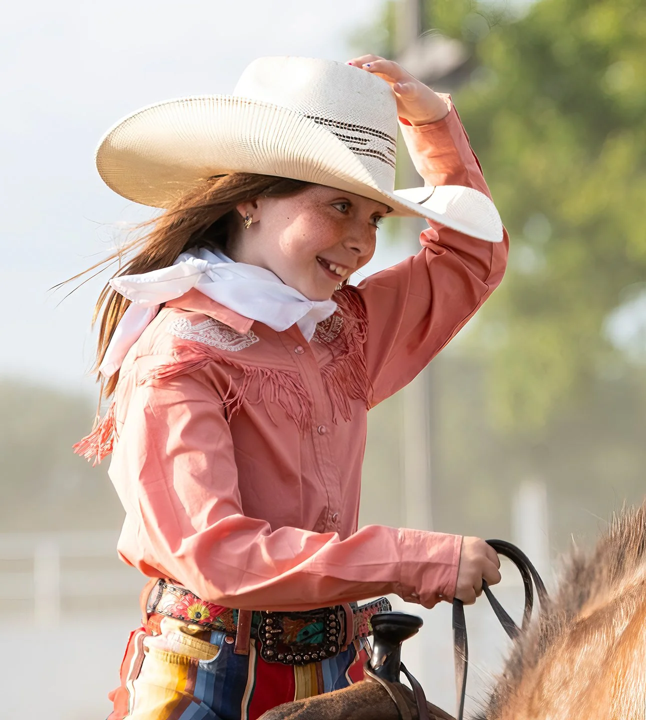 A young woman adjusts her Stetson at a rodeo in Vermont. Photo by Josh Trudell