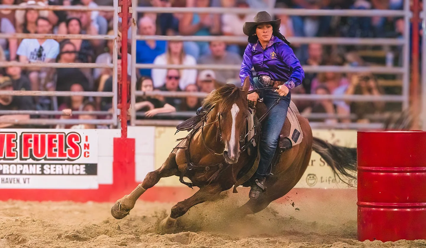 A woman races a horse around barrels at a rodeo in Vermont. Photo by Josh Trudell