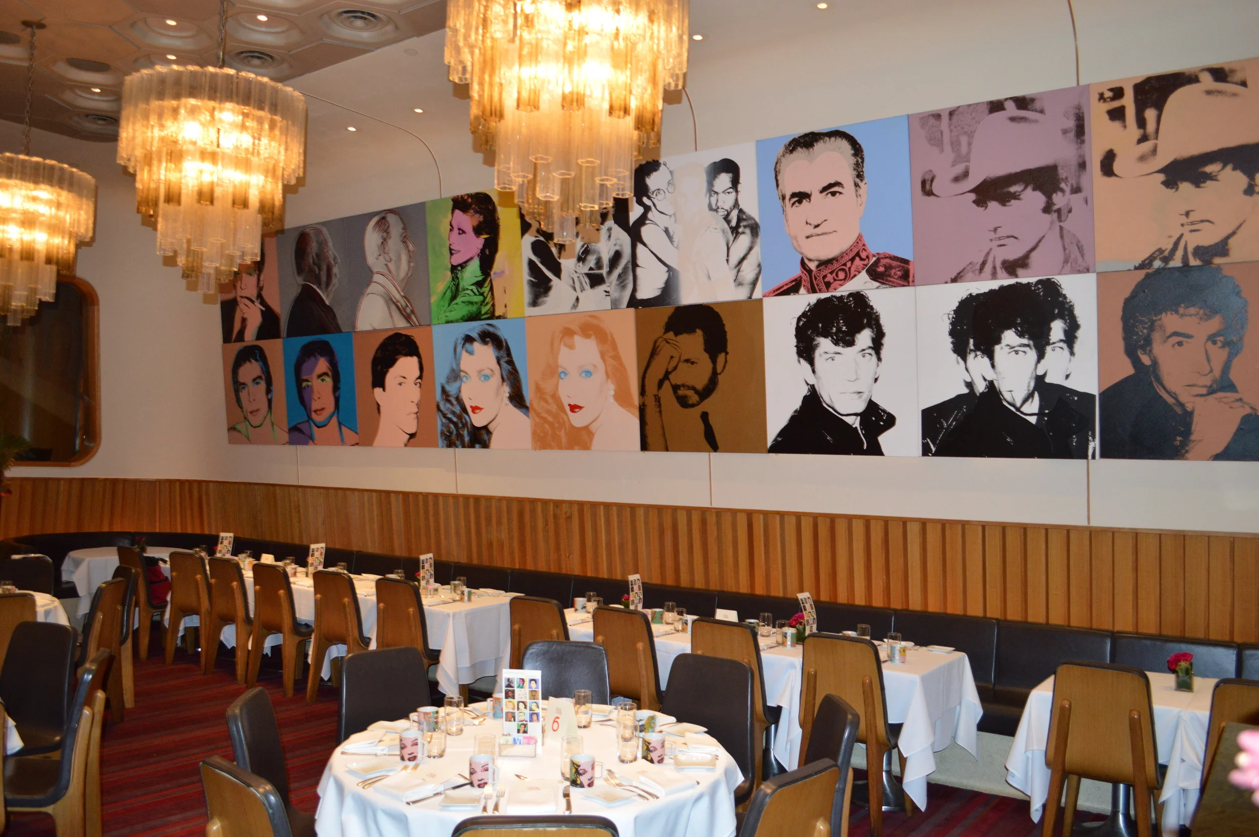 The main dining room of Casa Lever with its series of Warhol's Portraits. On each table, a card of unidentified portraits to facilitate a table guessing game; a completed answer sheet was passed around at dessert. On every menu, Warhol quotations to encourage conversation on Warhol's philosophy.