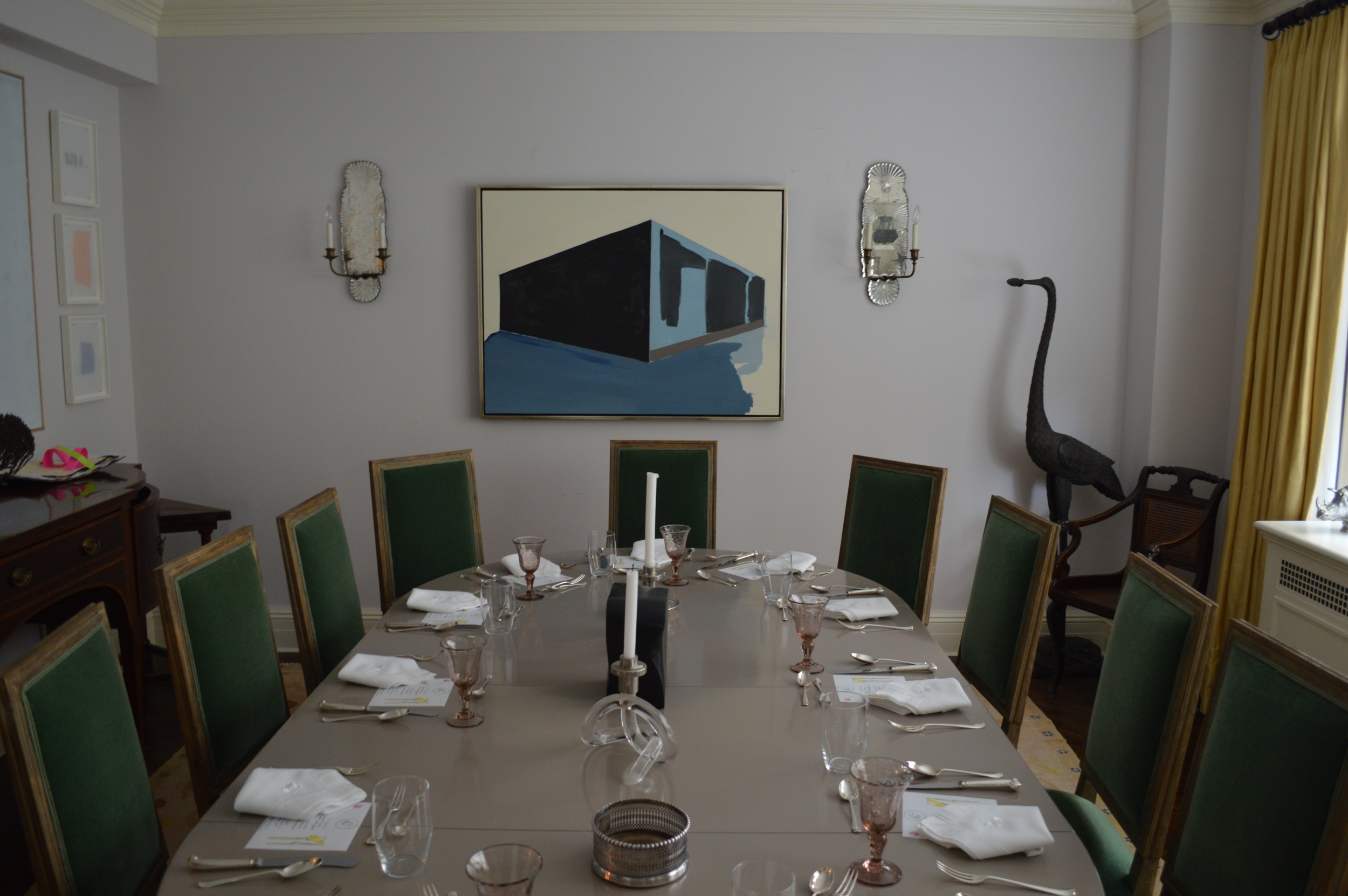 The table set for 12 members and guests, surrounded by painting and sculpture. 