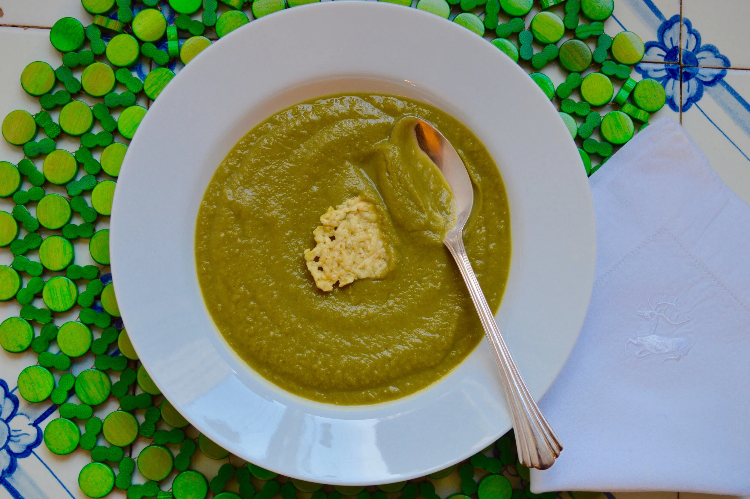 Broccoli Soup garnished with a parmesan crisp. Placemat by Kim Seybert. 