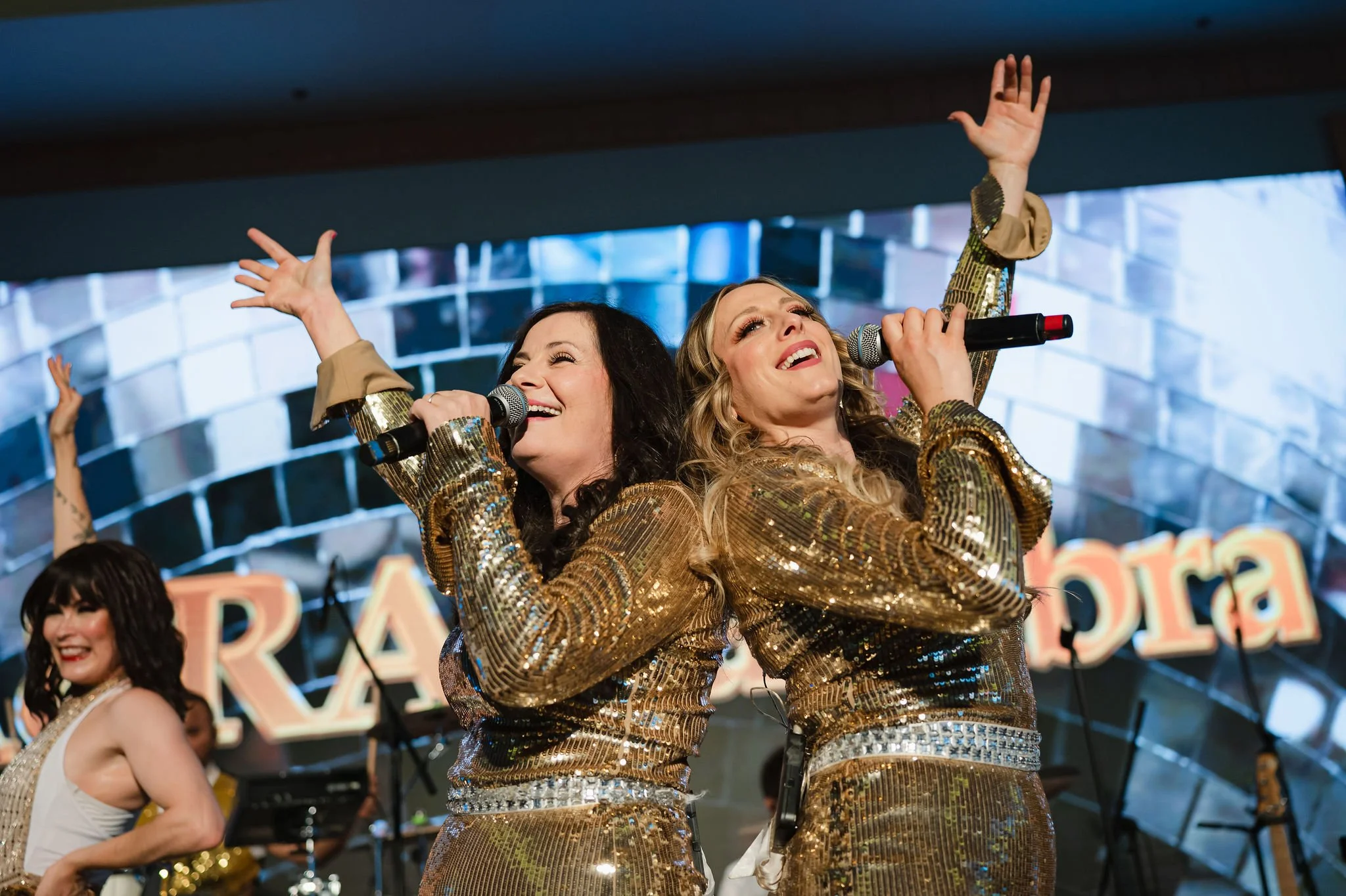 Two singers performing in matching gold outfits