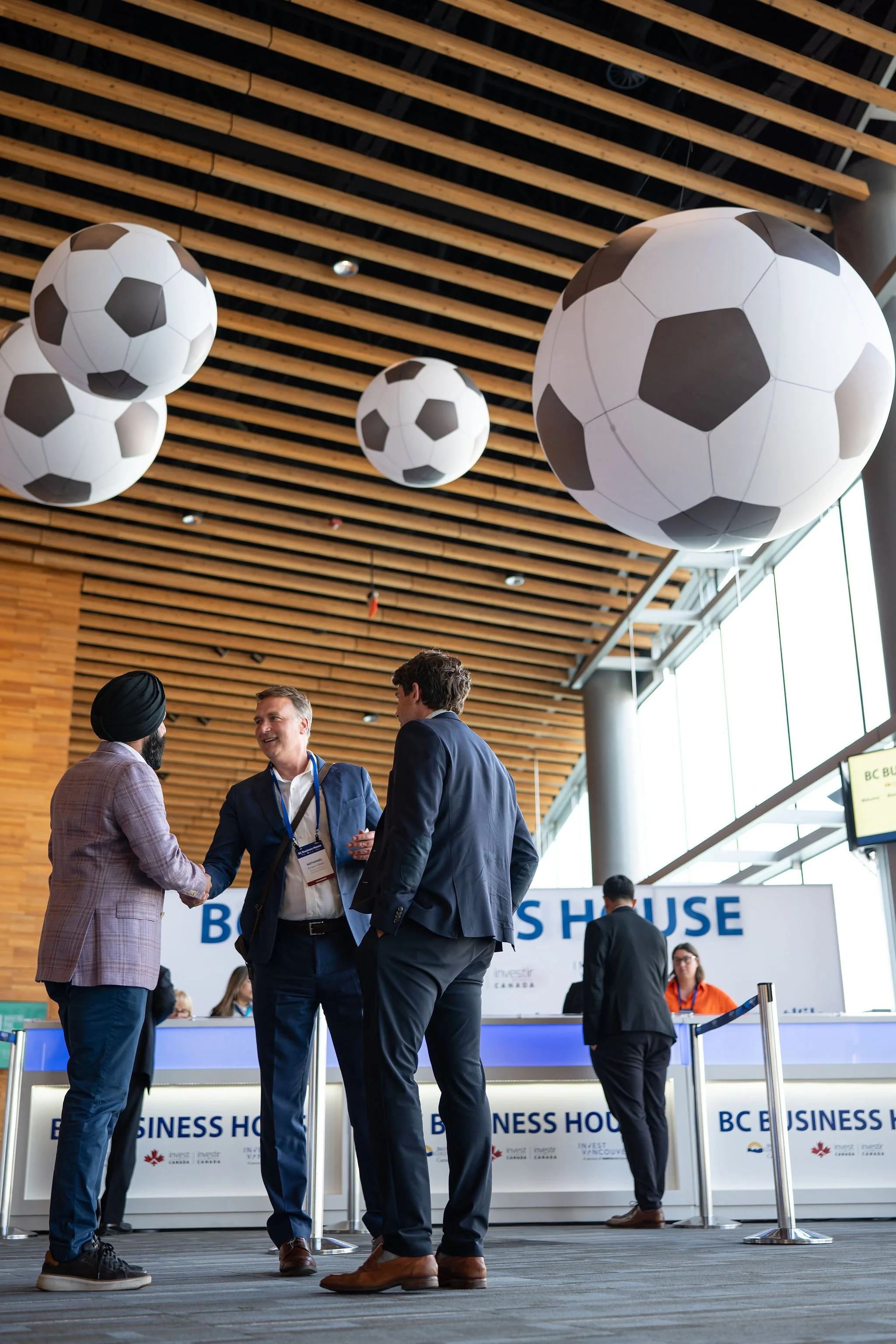 Business guests networking beneath soccer-themed event decor