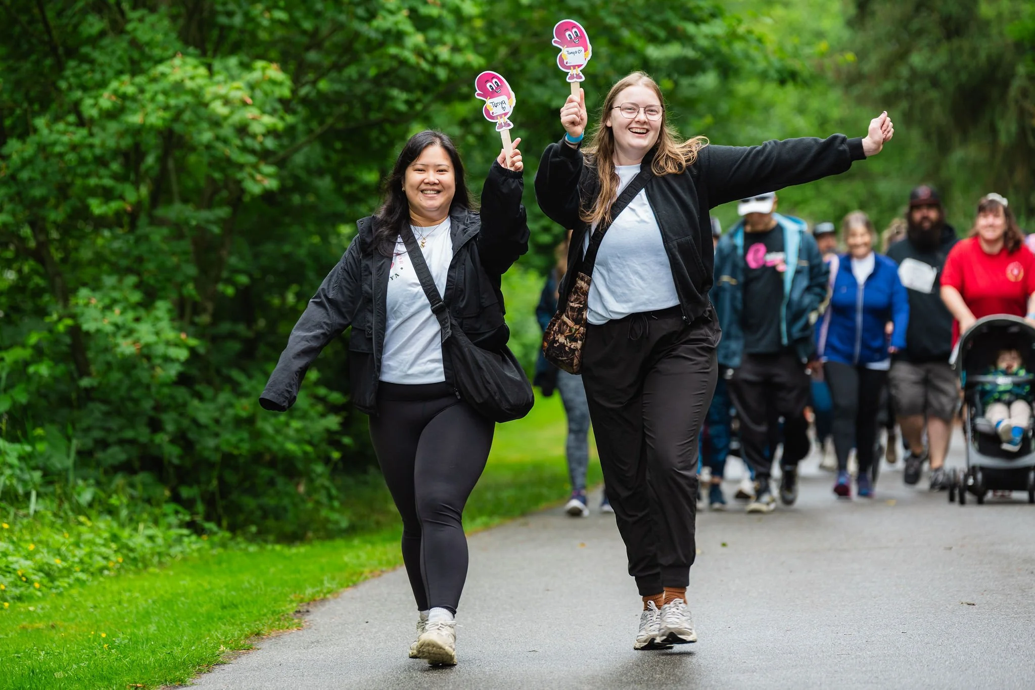 Charity walk participants celebrating along a park trail