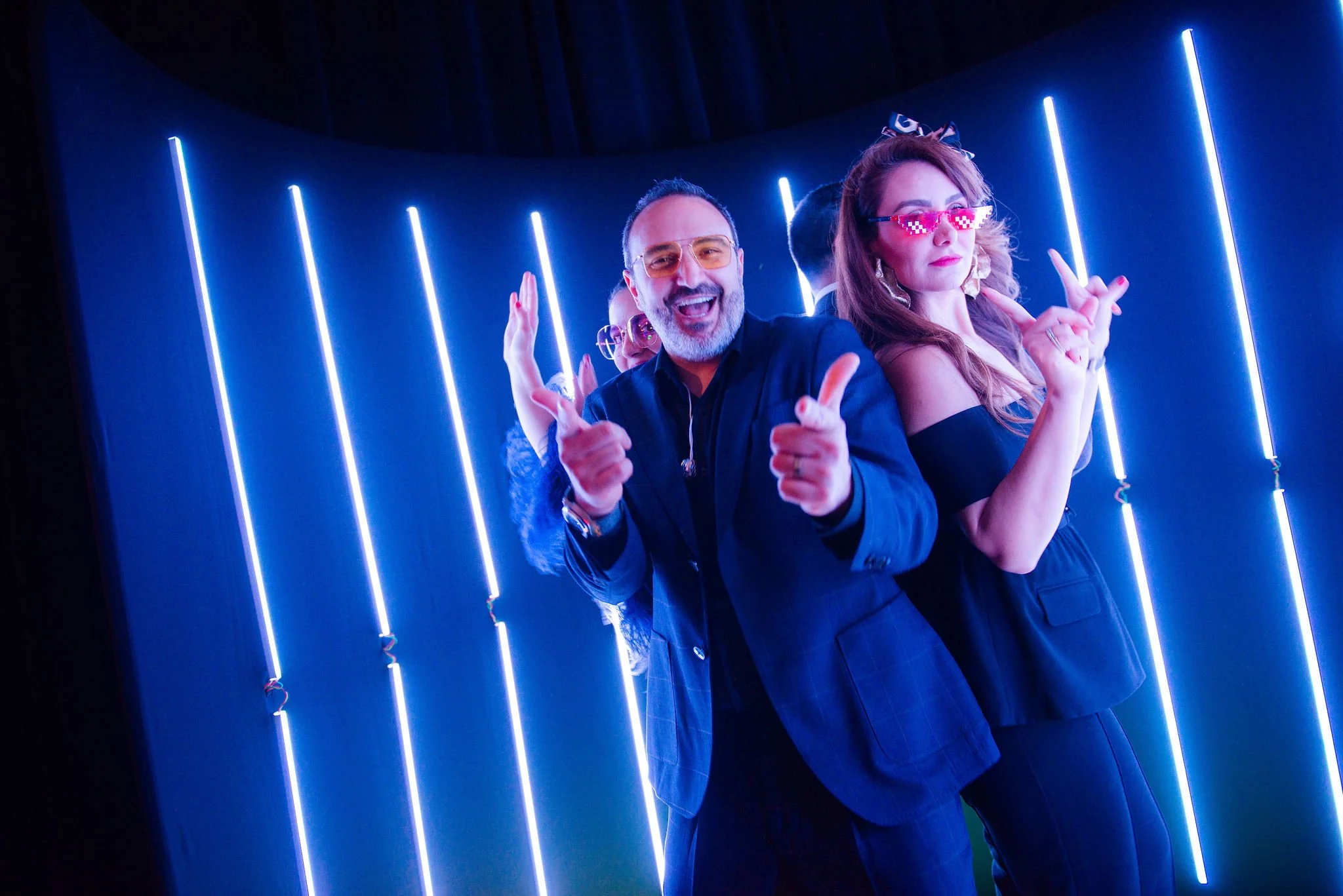 Guests posing inside a blue LED photo booth at a gala